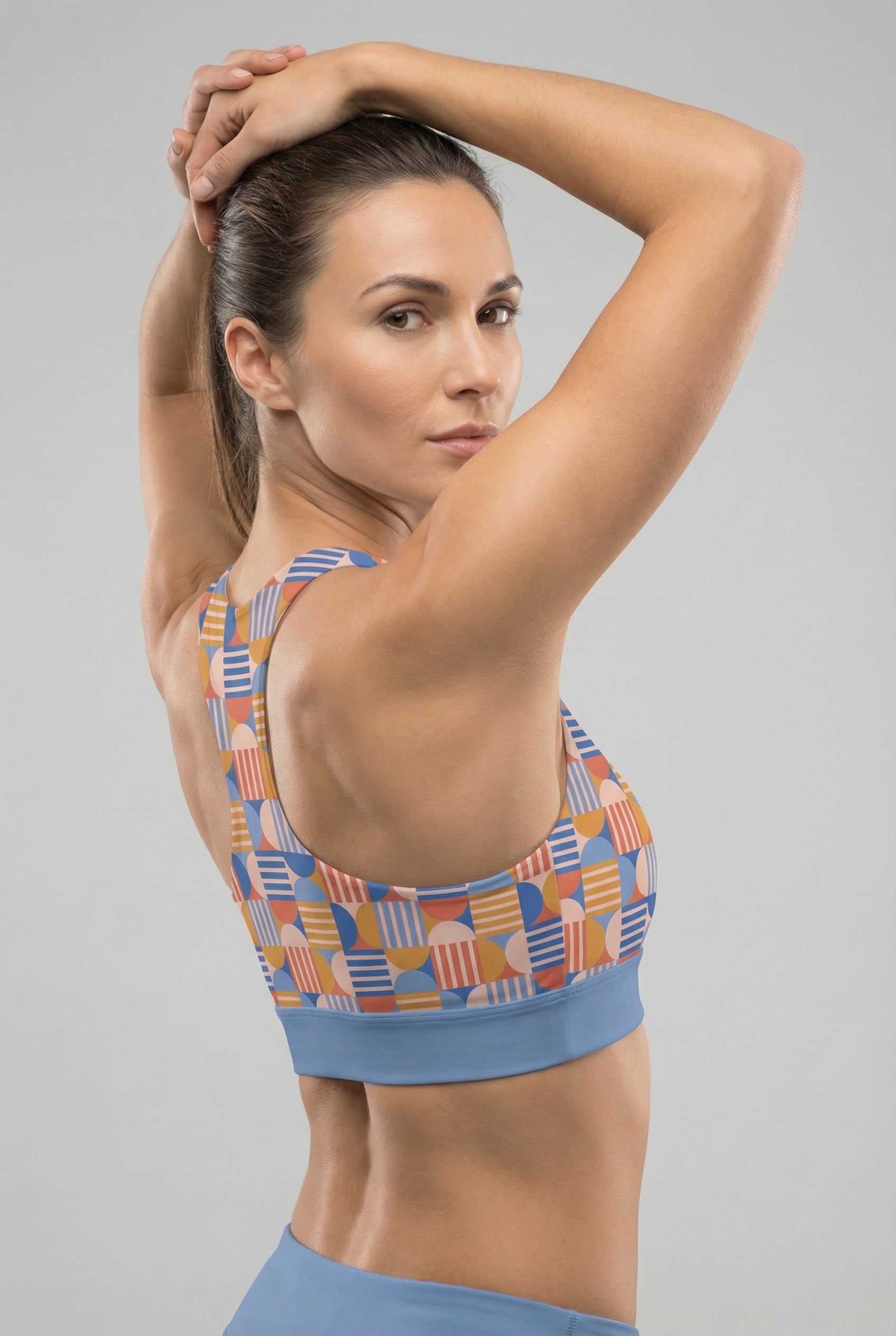 Woman wearing a patterned sports bra and shorts on a gray background