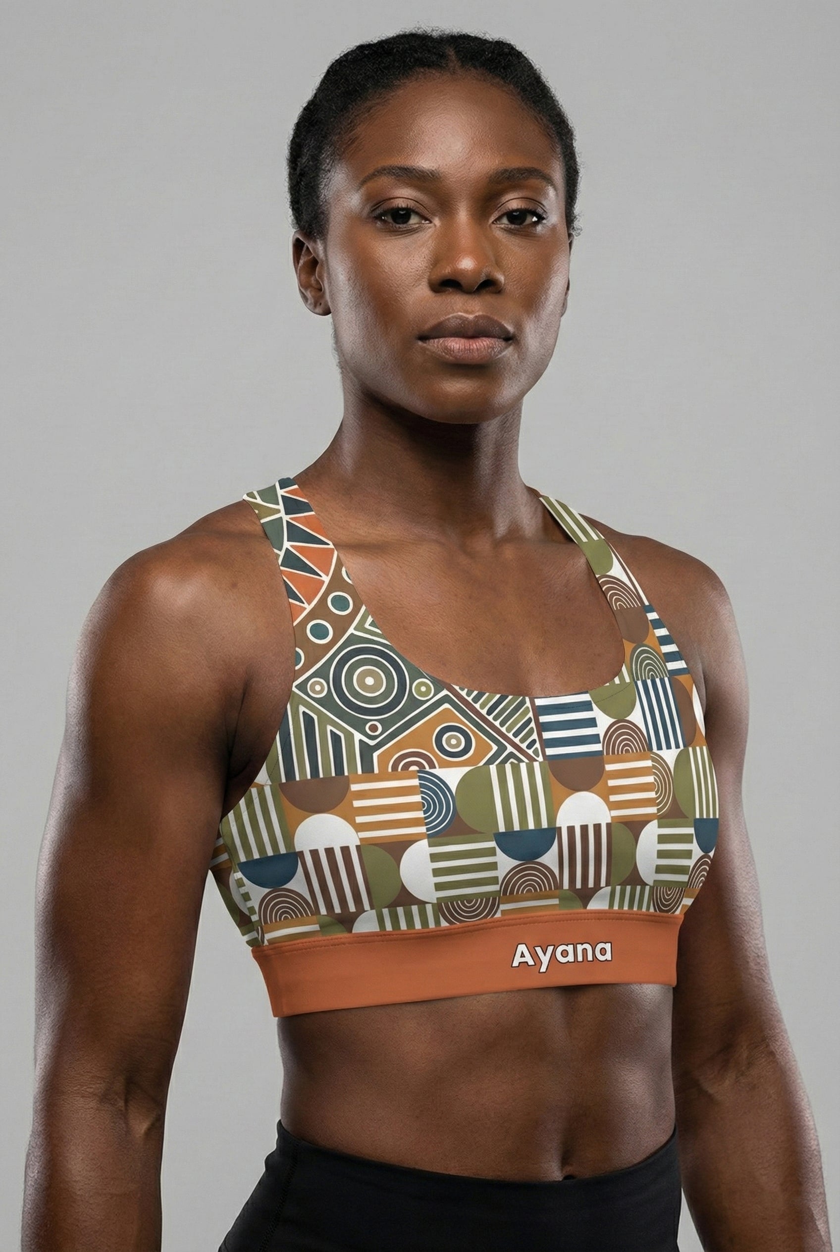 Front view of tribal geometric sports bra featuring olive green and orange patterns, with the name 'Ayana' printed on the terracotta waistband.