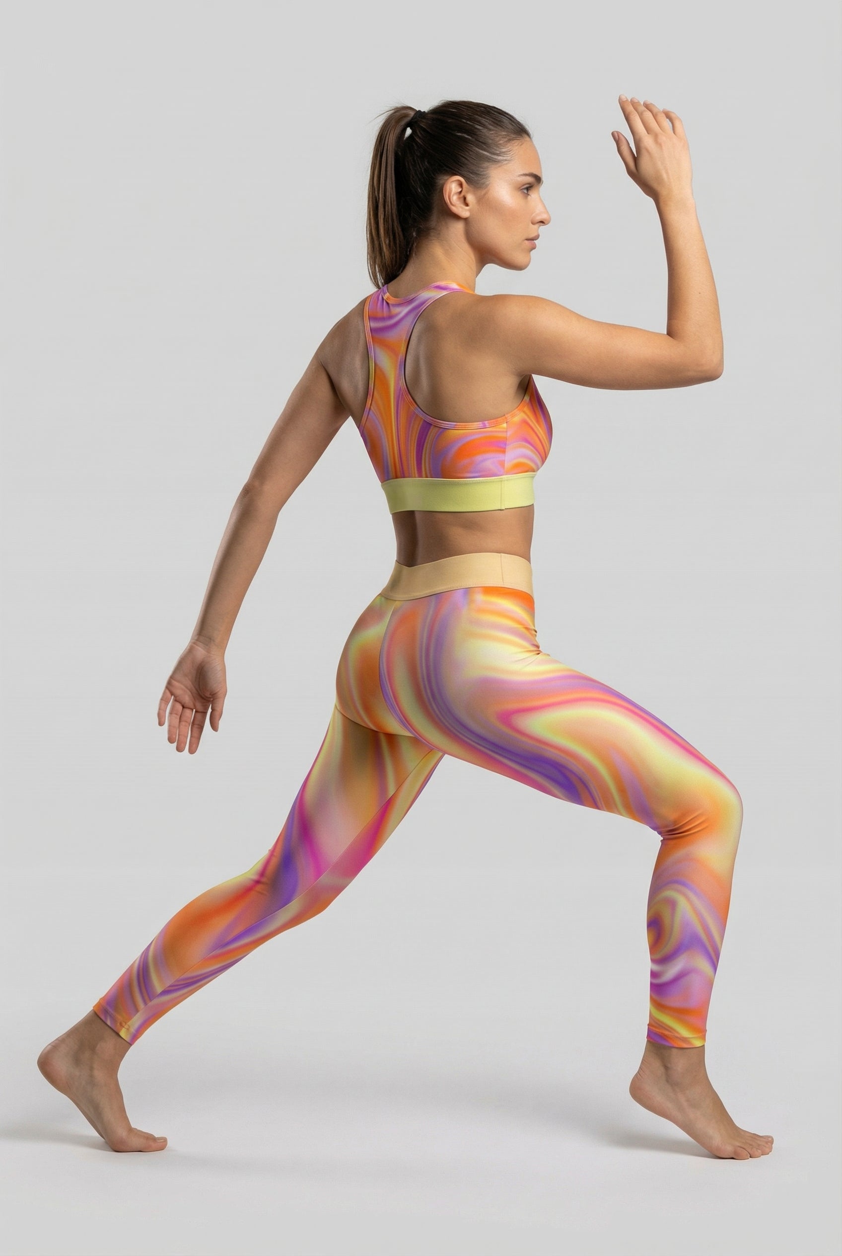 Front view of tie-dye sports bra with orange, purple, and yellow swirl pattern, featuring 'VORTEX' printed on the pastel yellow waistband.
