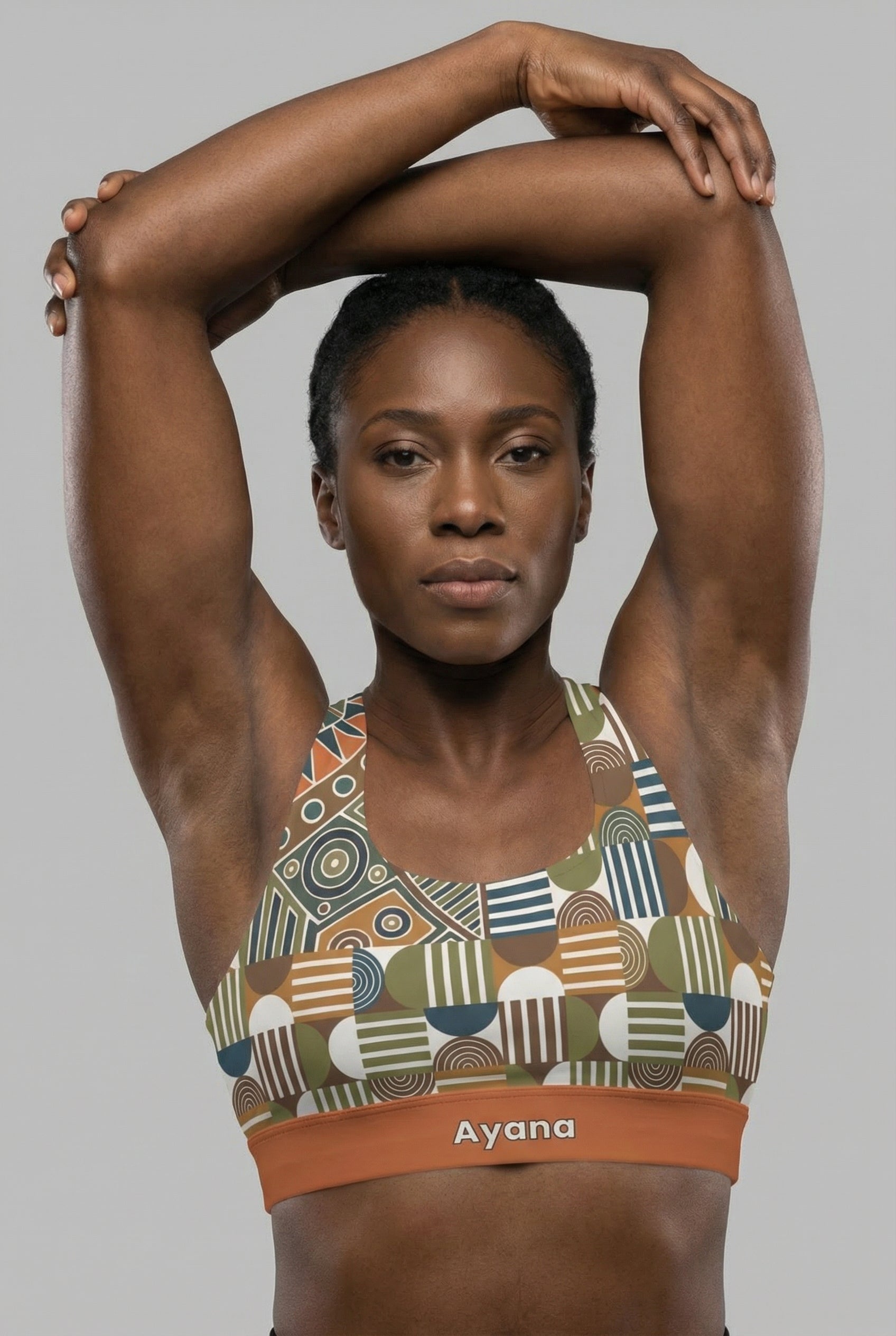 Front view of tribal geometric sports bra featuring olive green and orange patterns, with the name 'Ayana' printed on the terracotta waistband.