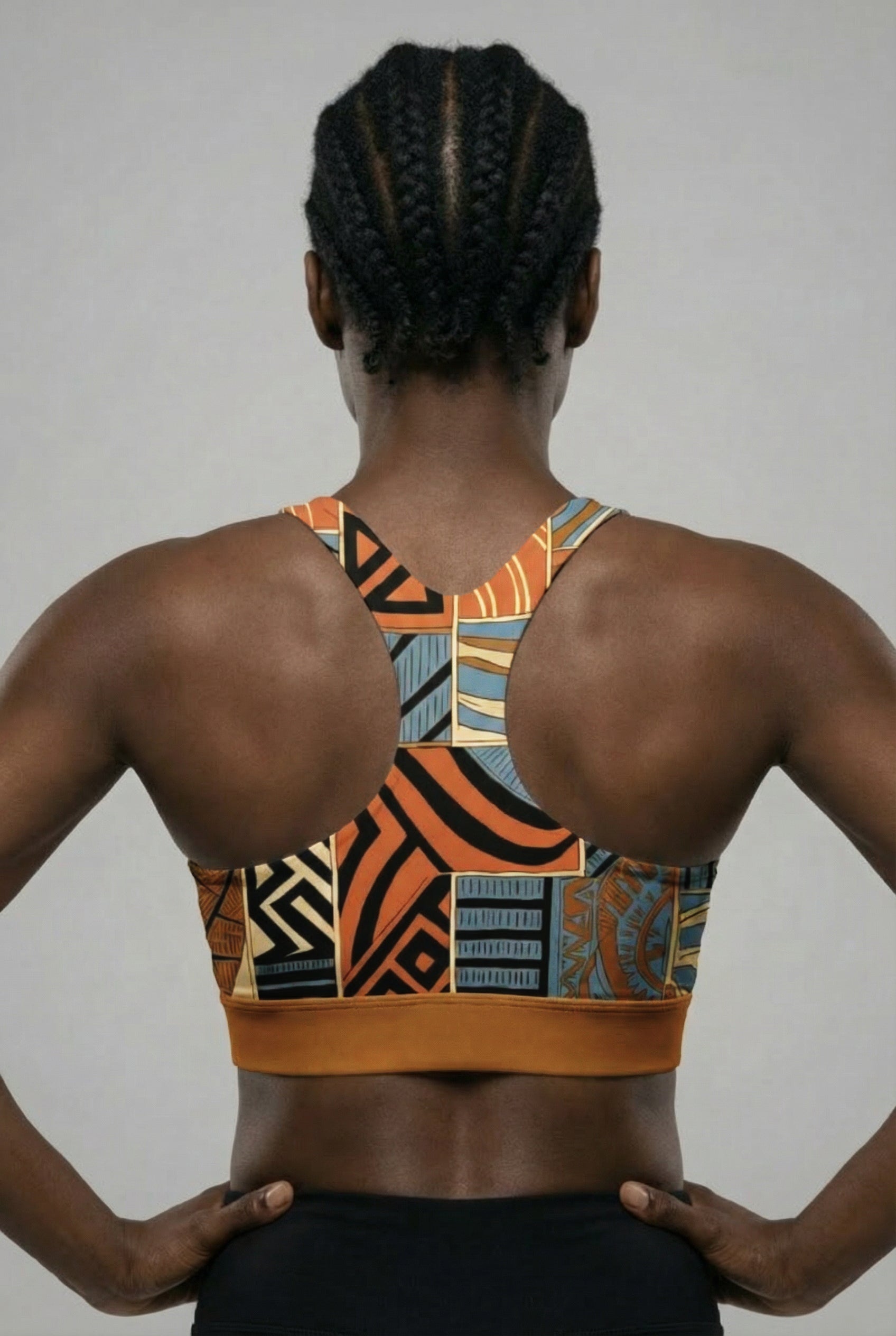Person wearing a patterned sports bra with hands on hips against a plain background