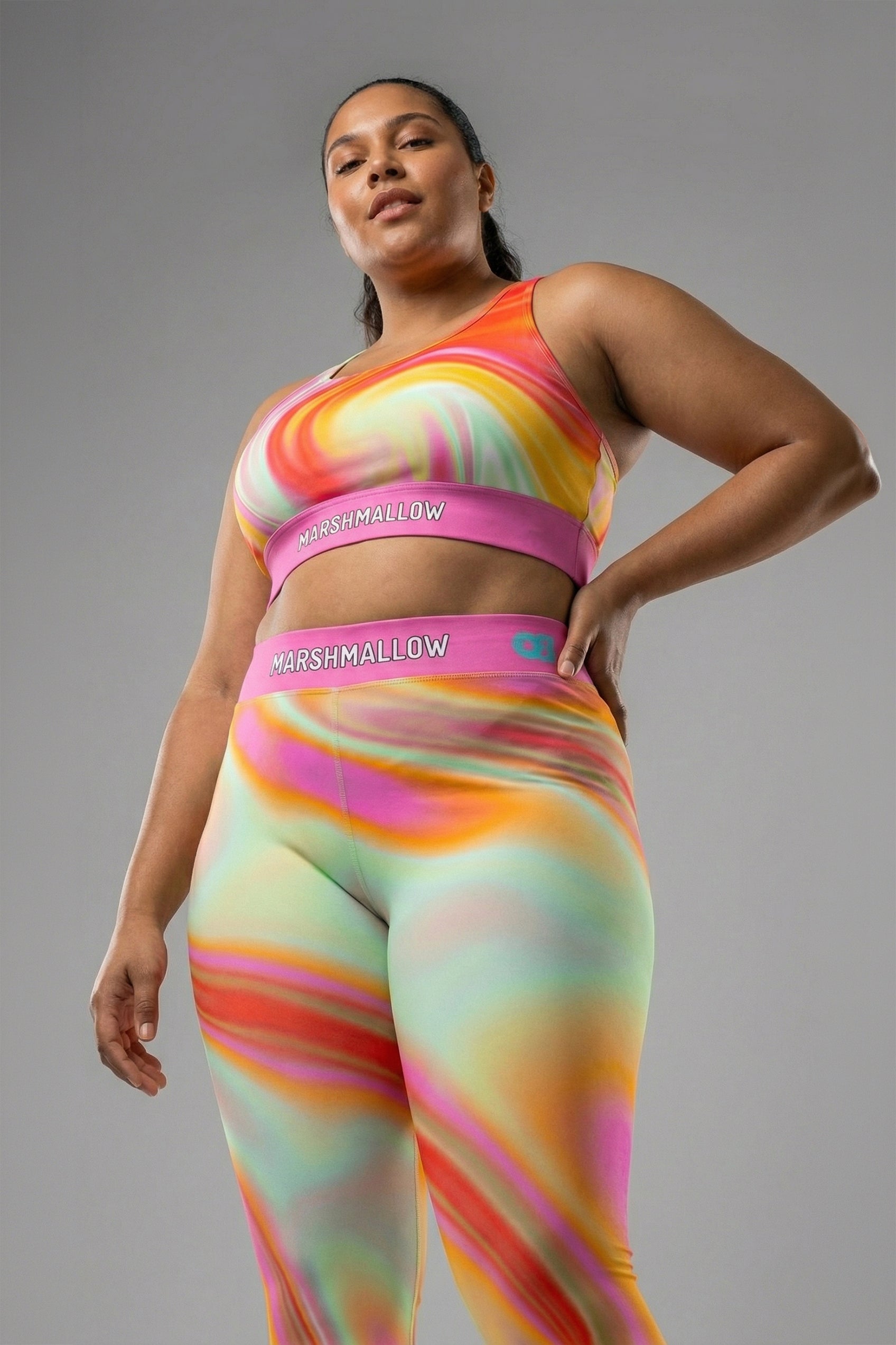 Front view of pastel tie-dye sports bra in peach, yellow, mint, and pink, featuring 'MARSHMALLOW' printed on the bubblegum pink waistband.