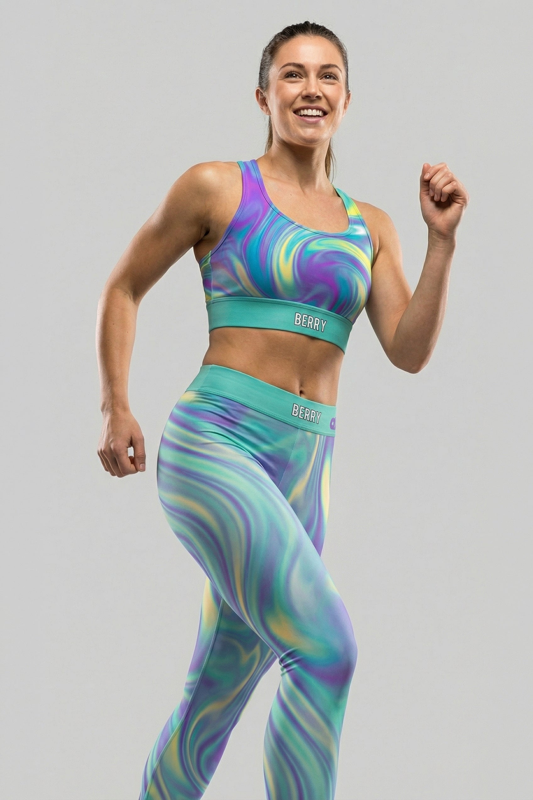 Front view of tie-dye sports bra in purple, mint green, and yellow swirls, featuring 'BERRY' printed on the solid mint waistband.