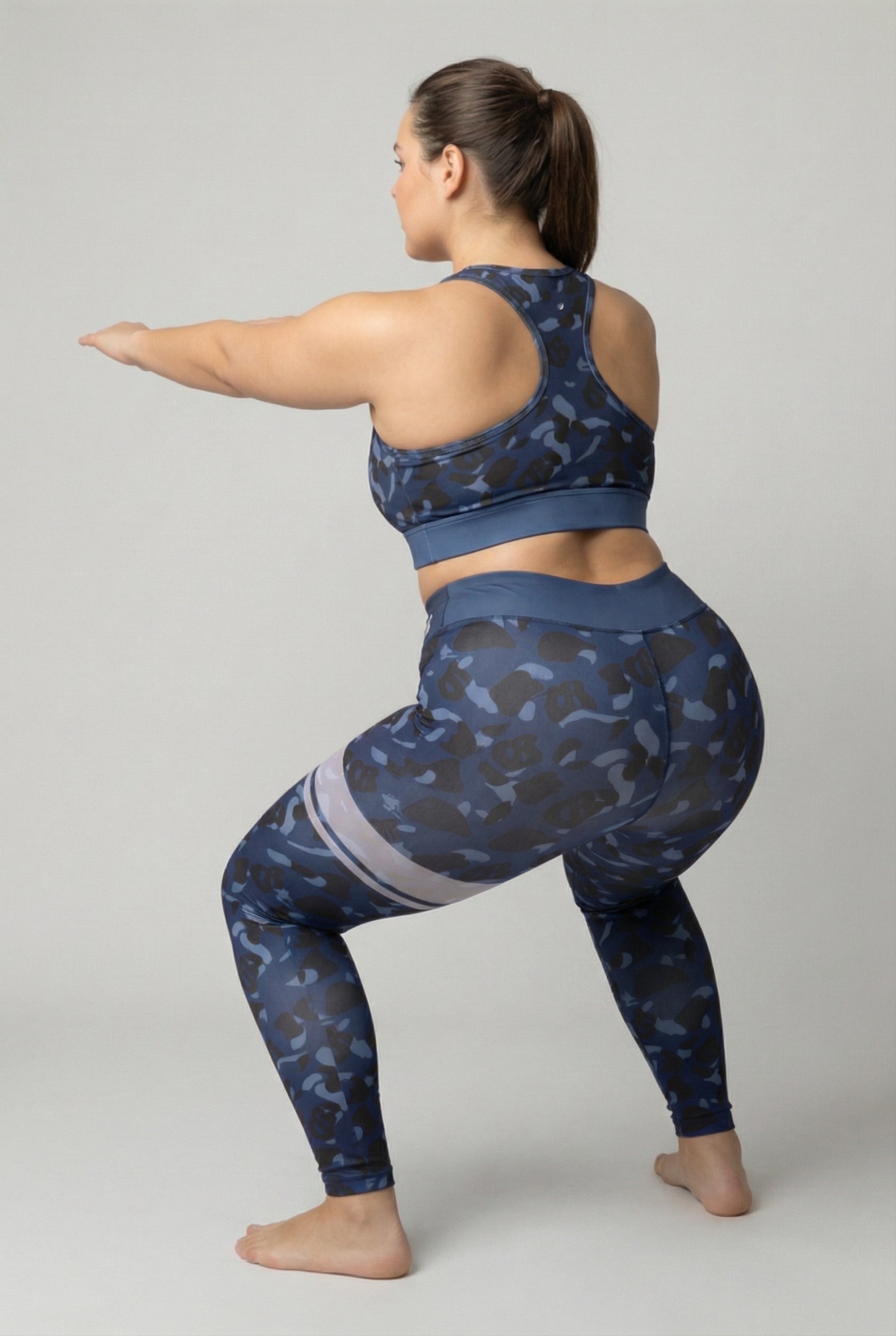 Front view of navy blue camouflage sports bra featuring hidden 'OB' monogram shapes in dark blue and black, with 'MIMOSA' printed on the navy waistband.