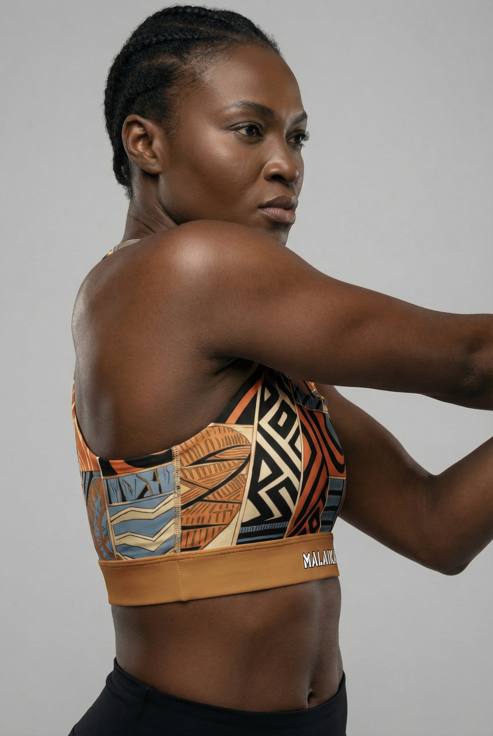 Woman wearing a patterned sports bra with visible brand name on a gray background