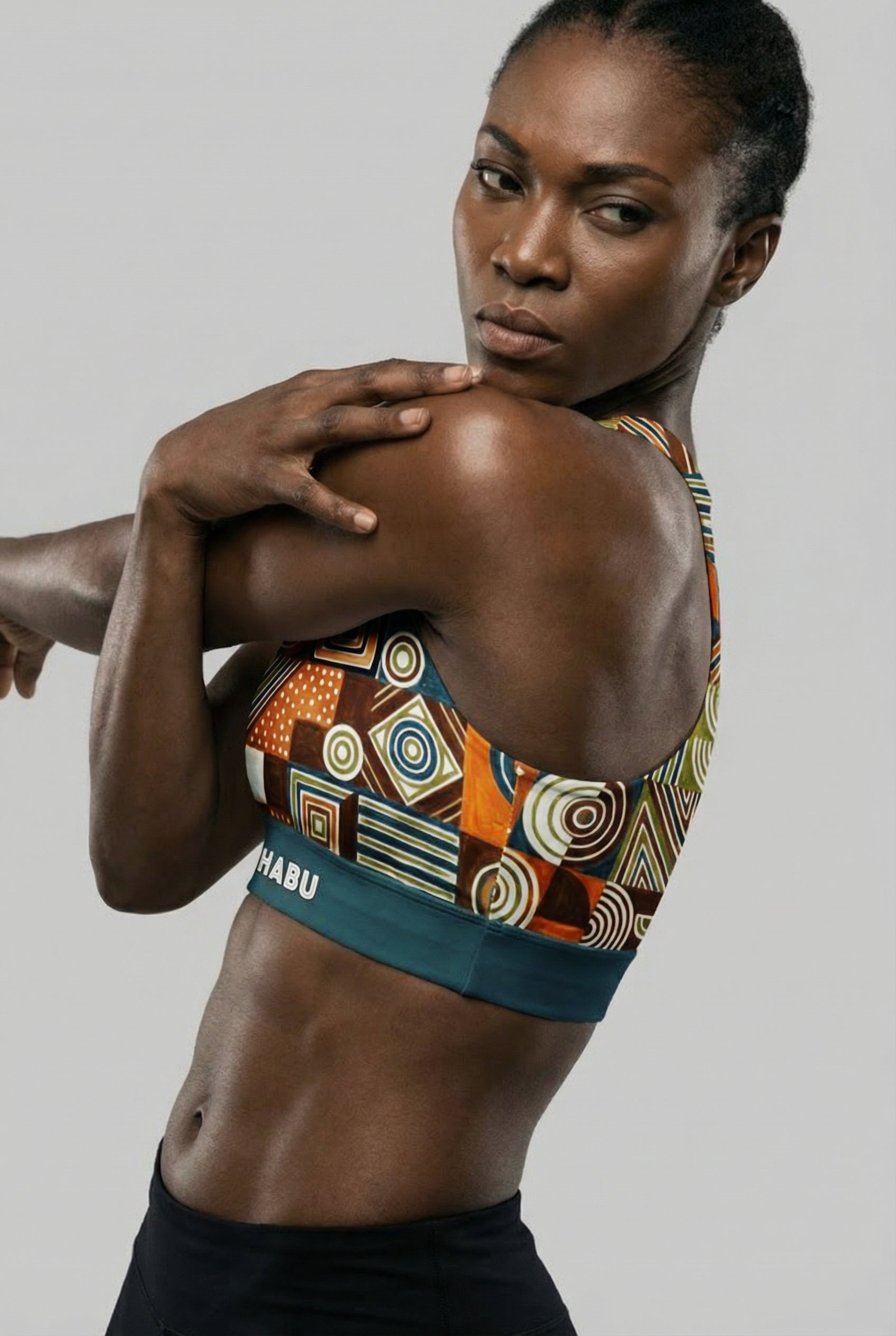 Woman wearing a patterned sports bra with visible brand name on a plain background