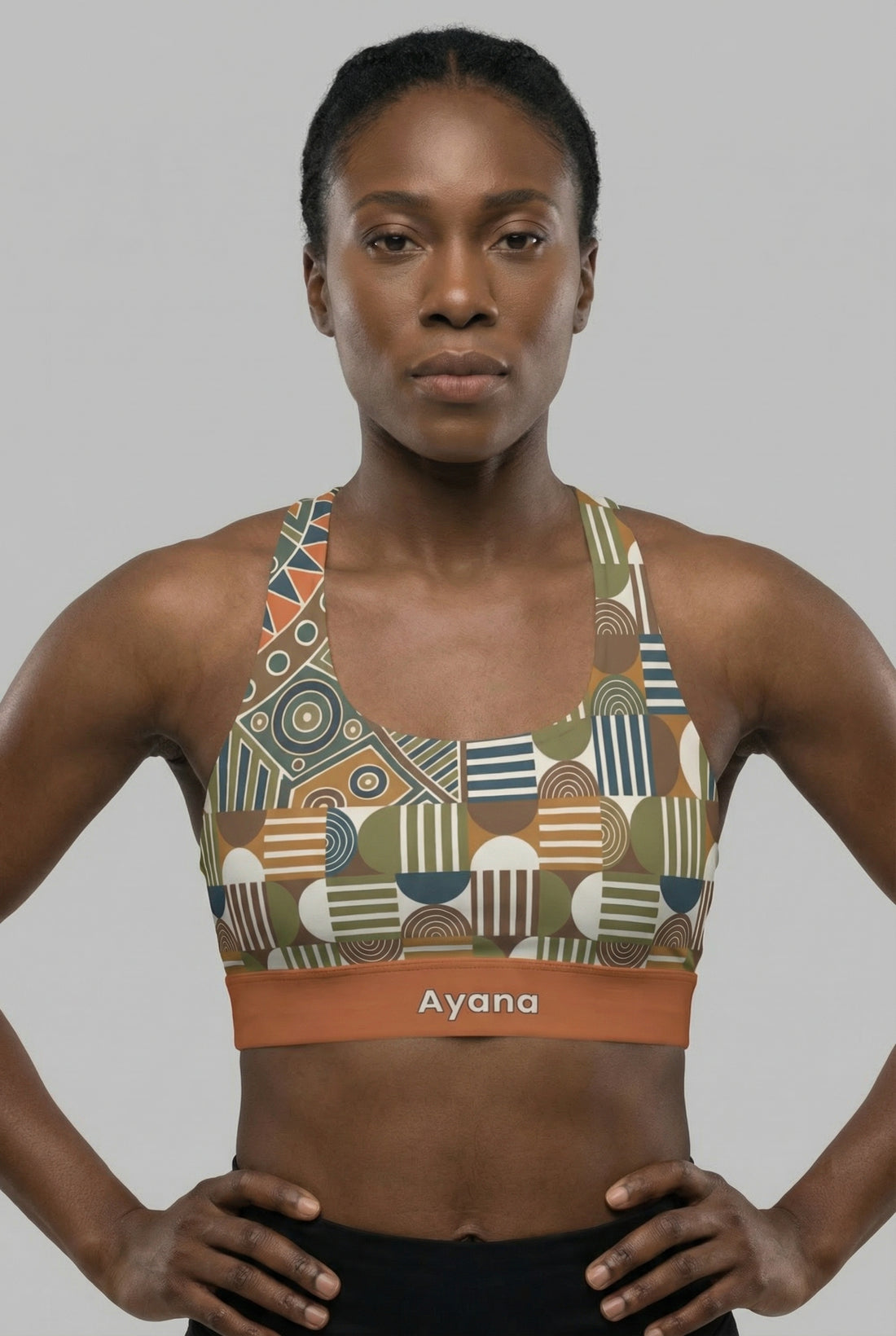 Front view of tribal geometric sports bra featuring olive green and orange patterns, with the name 'Ayana' printed on the terracotta waistband.