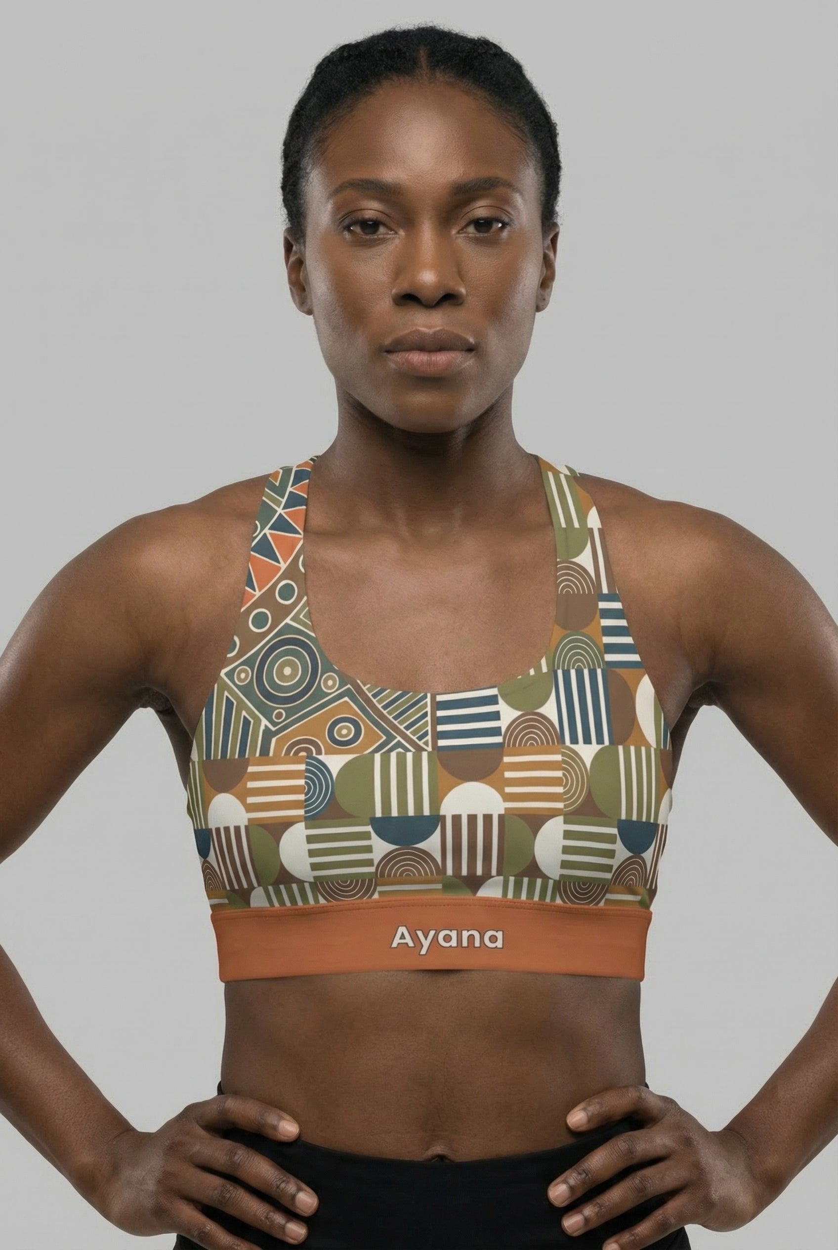 Front view of tribal geometric sports bra featuring olive green and orange patterns, with the name 'Ayana' printed on the terracotta waistband.