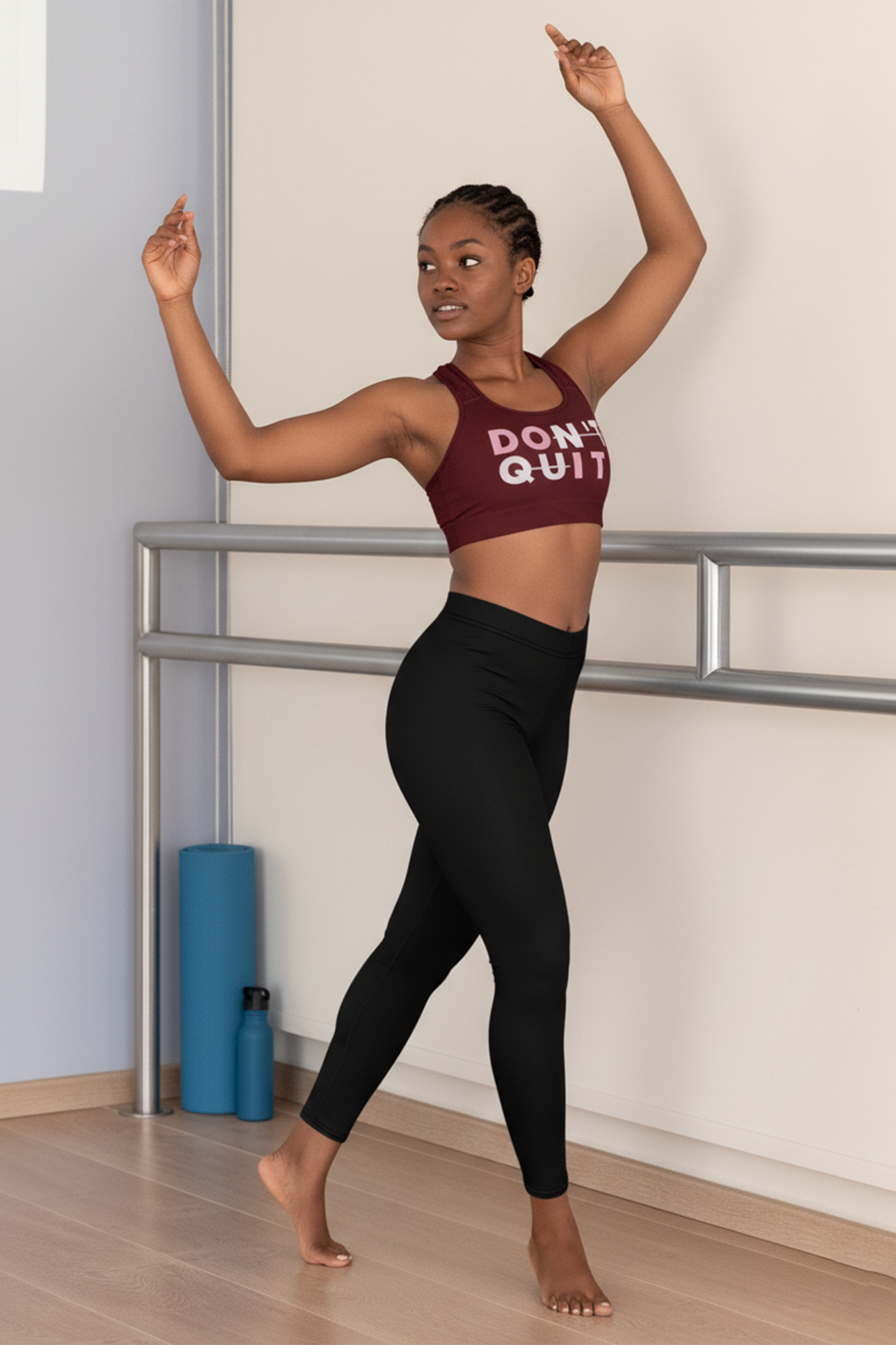 Person in maroon sports bra and black leggings with 'Don't Quit' text, standing in a dance pose in a studio.