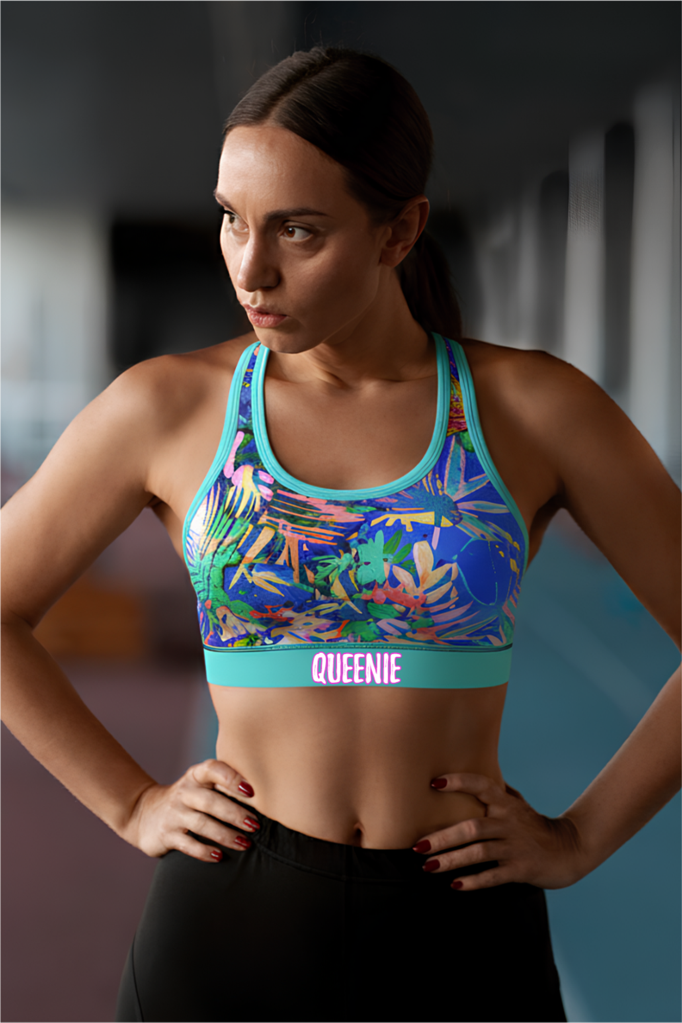 Woman wearing a colorful sports bra with 'QUEENIE' branding in an indoor setting.