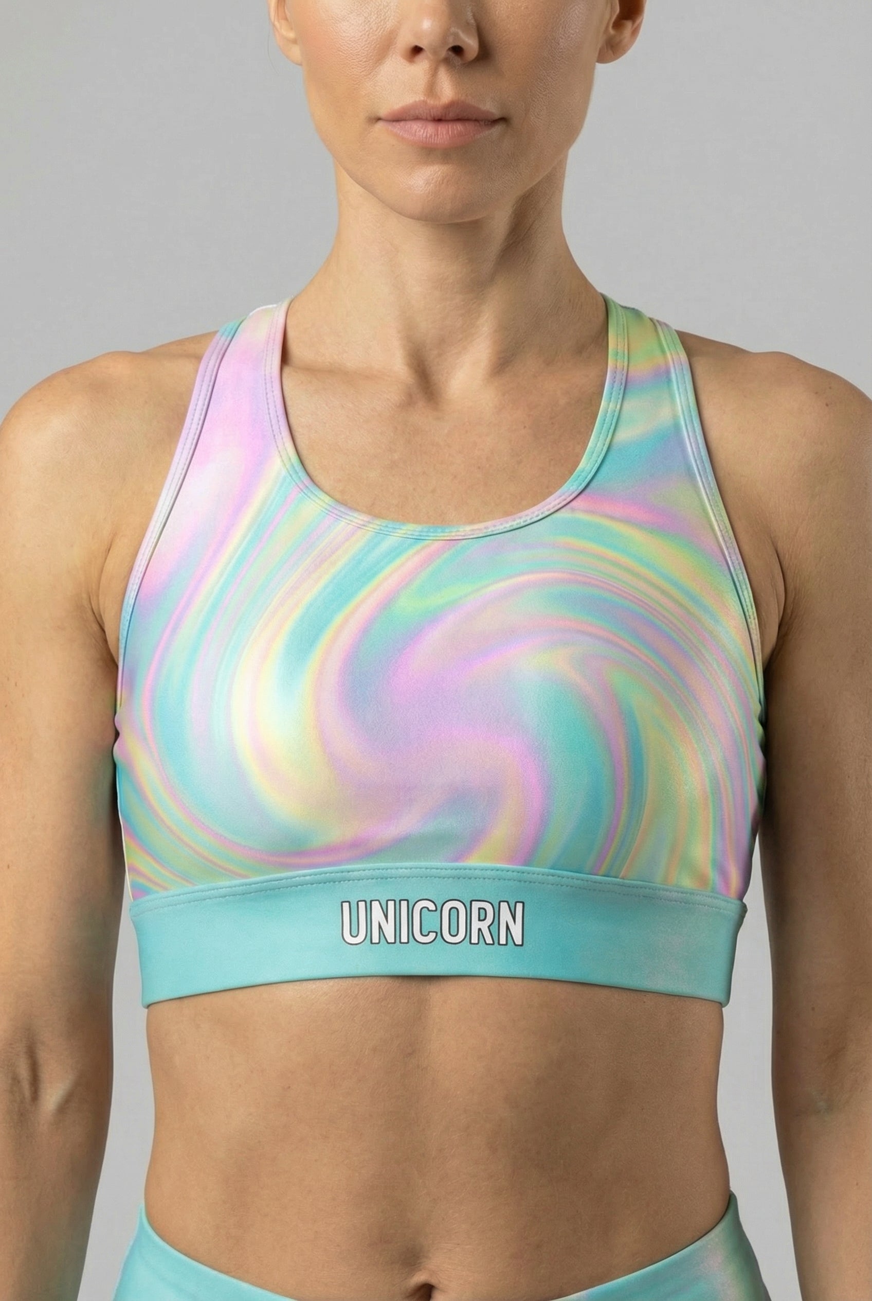 Front view of pastel tie-dye swirl sports bra in light pink, aqua, and pale yellow, featuring 'UNICORN' printed on the light aqua waistband.