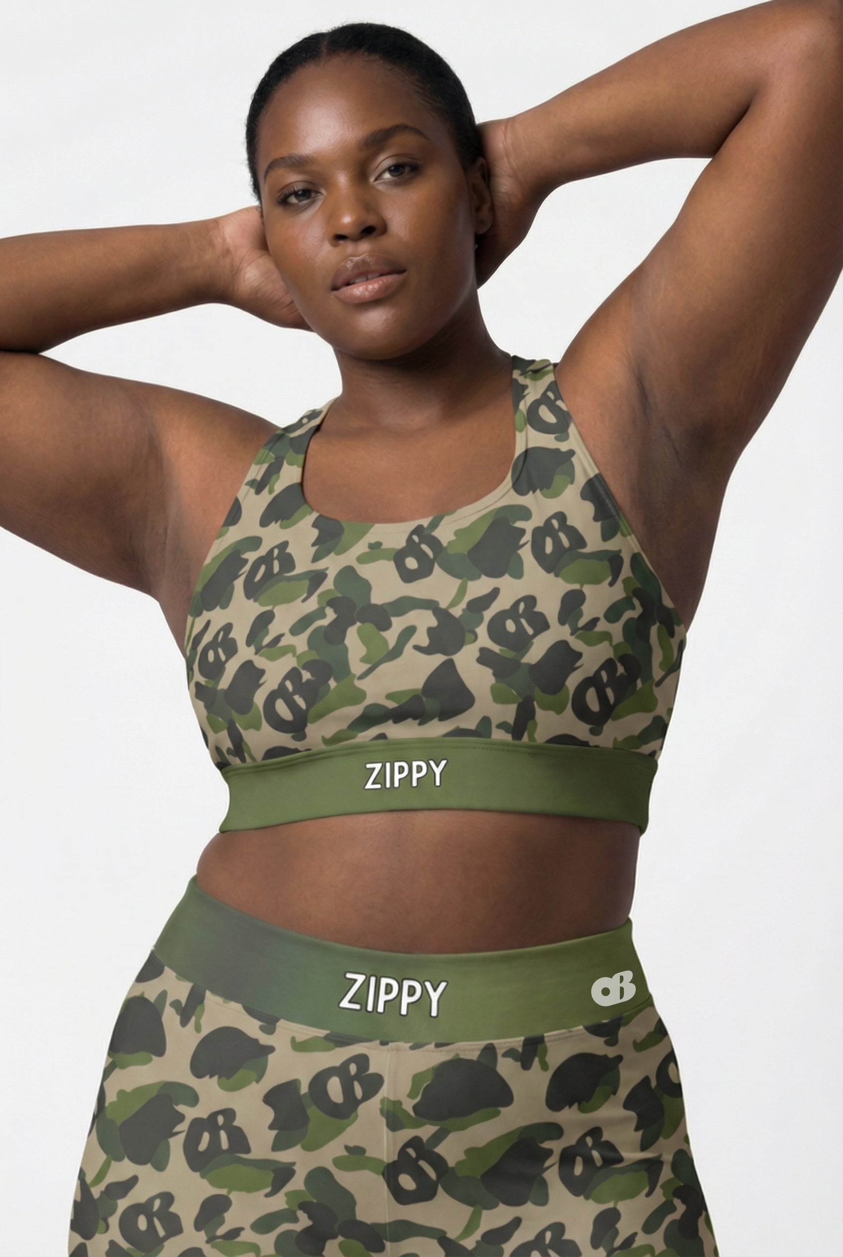 Front view of green camouflage sports bra featuring hidden 'OB' monogram shapes in olive and tan, with 'ZIPPY' printed on the olive green waistband.