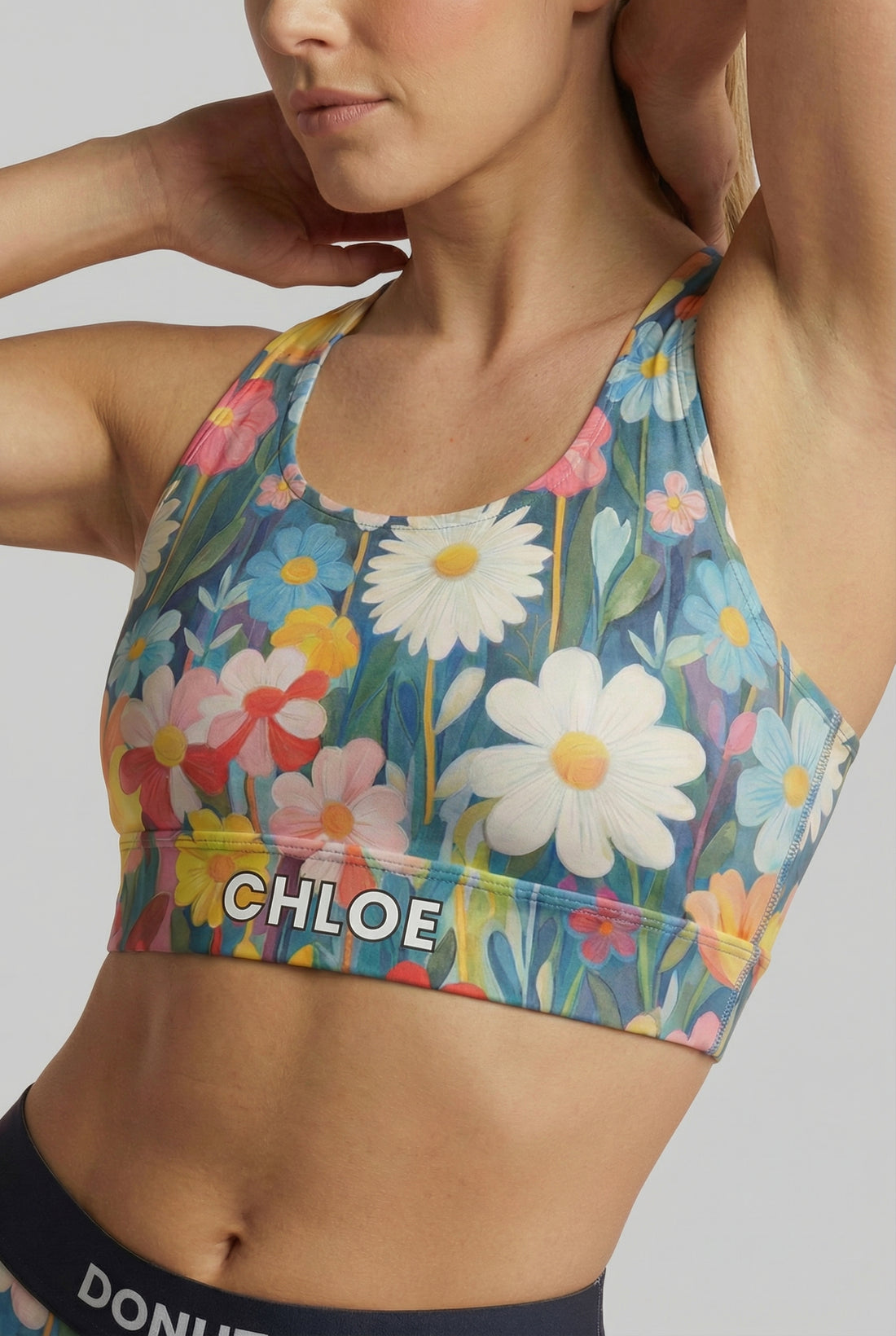 Watercolor floral sport bra with white daisies and custom name 'CHLOE' on waistband.