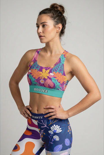 Purple and teal sport bra with stylized tropical leaf print and custom text 'BOUJEE' on waistband.
