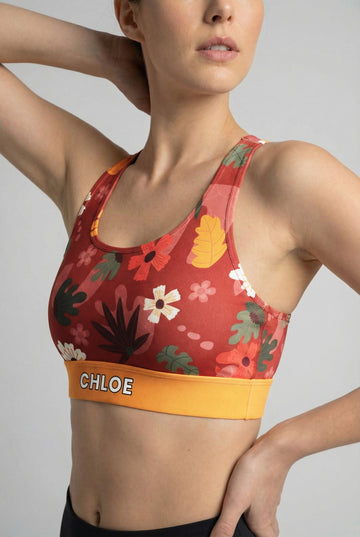 Deep red sport bra with vintage floral print and custom name 'CHLOE' on mustard yellow waistband.