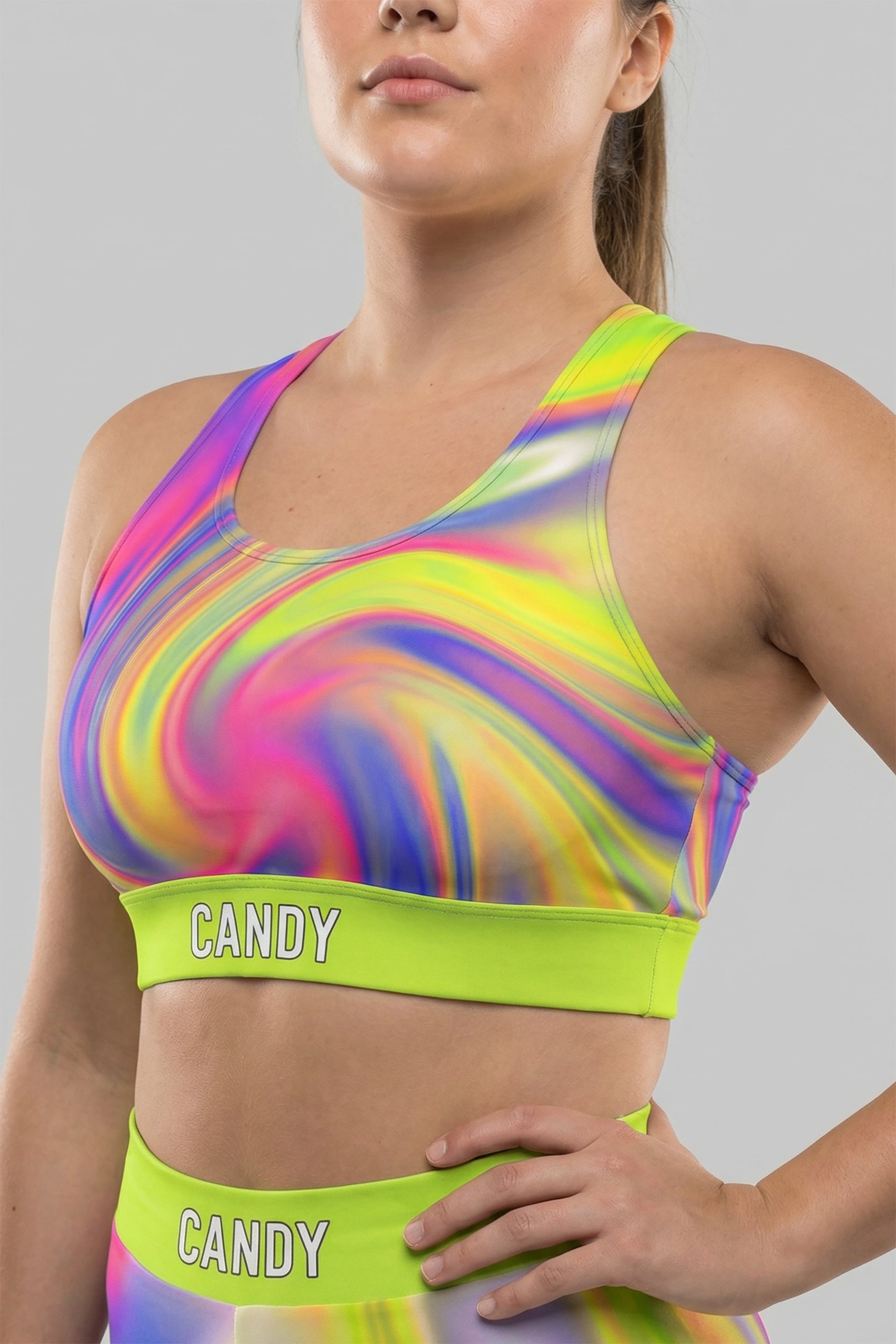 Front view of neon tie-dye sports bra in lime green, pink, and purple, featuring 'CANDY' printed on the bright neon lime waistband.
