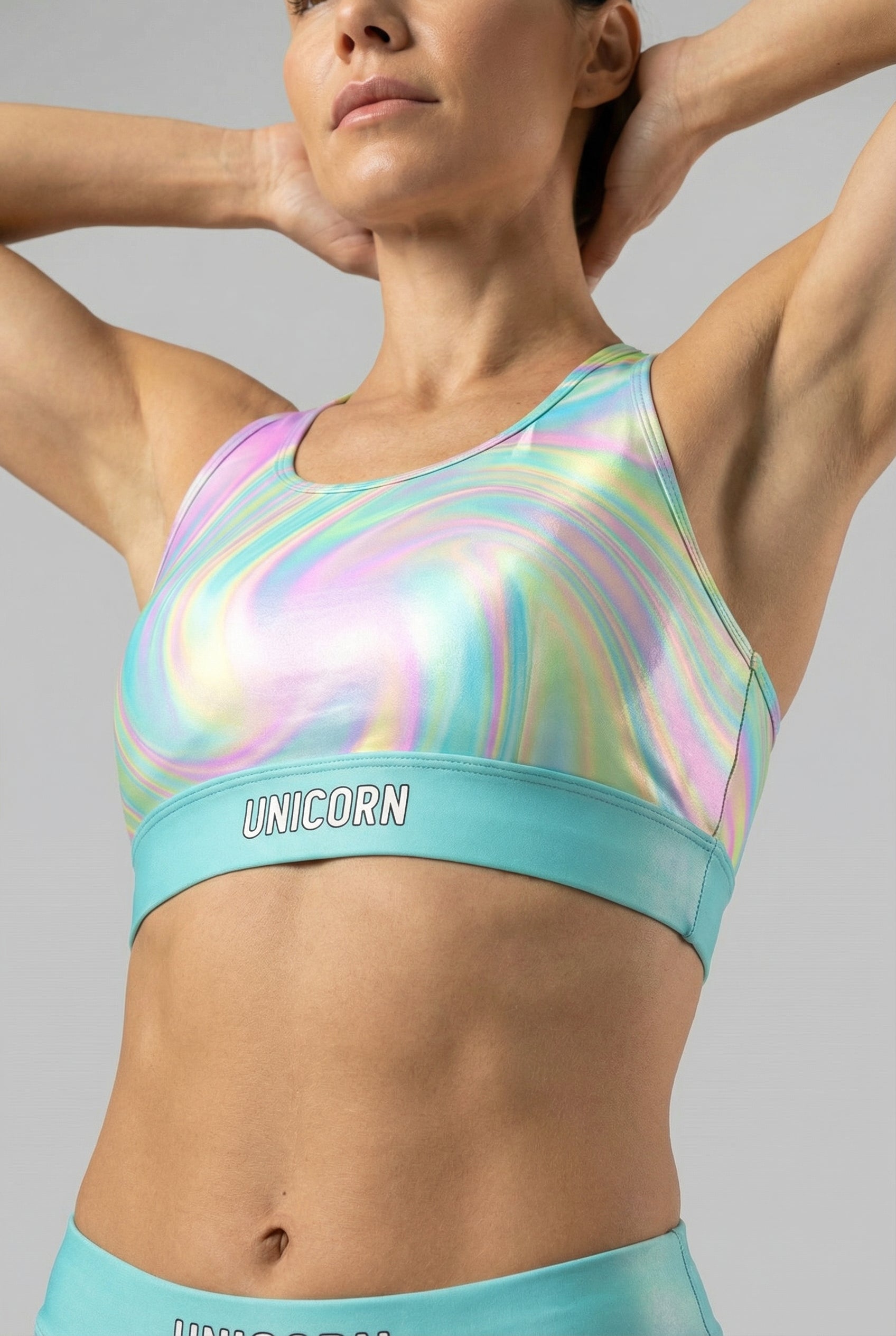 Front view of pastel tie-dye swirl sports bra in light pink, aqua, and pale yellow, featuring 'UNICORN' printed on the light aqua waistband.
