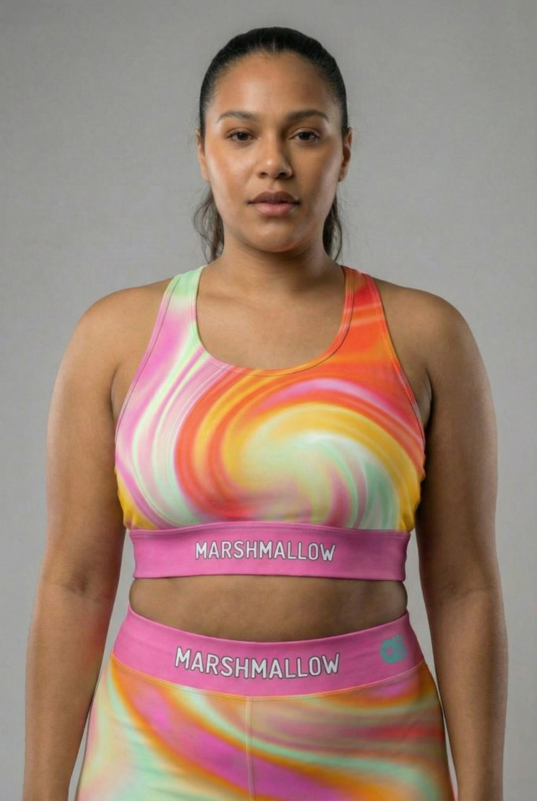 Front view of pastel tie-dye sports bra in peach, yellow, mint, and pink, featuring 'MARSHMALLOW' printed on the bubblegum pink waistband.