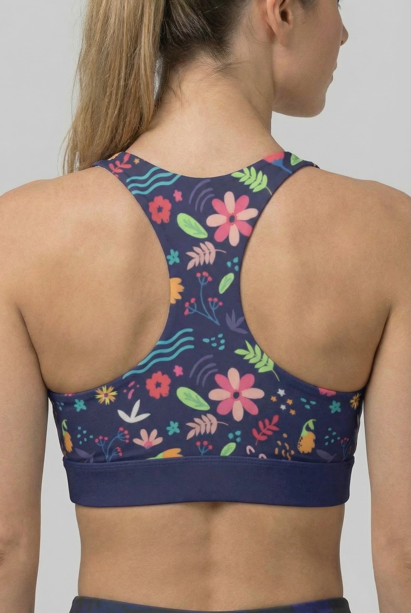 Navy sports bra with colorful floral pattern worn by a person on a plain background