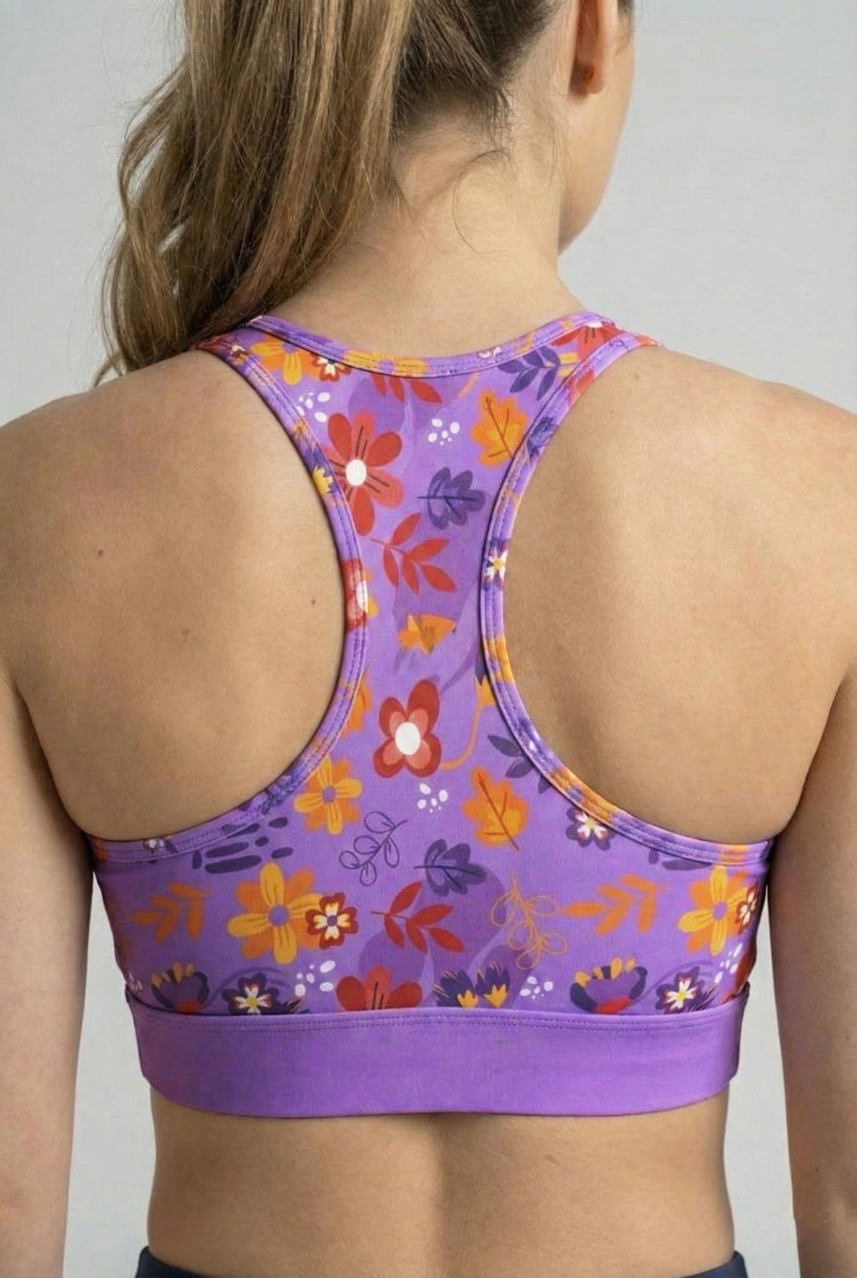 Woman wearing personalized purple floral sport bra with racerback fit.