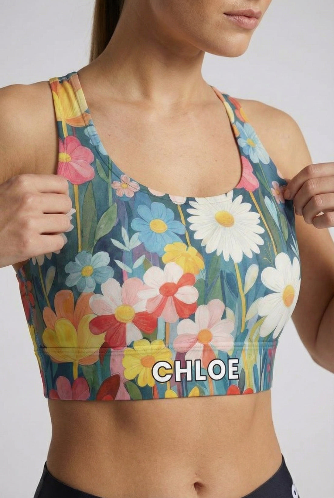 Watercolor floral sport bra with white daisies and custom name 'CHLOE' on waistband.