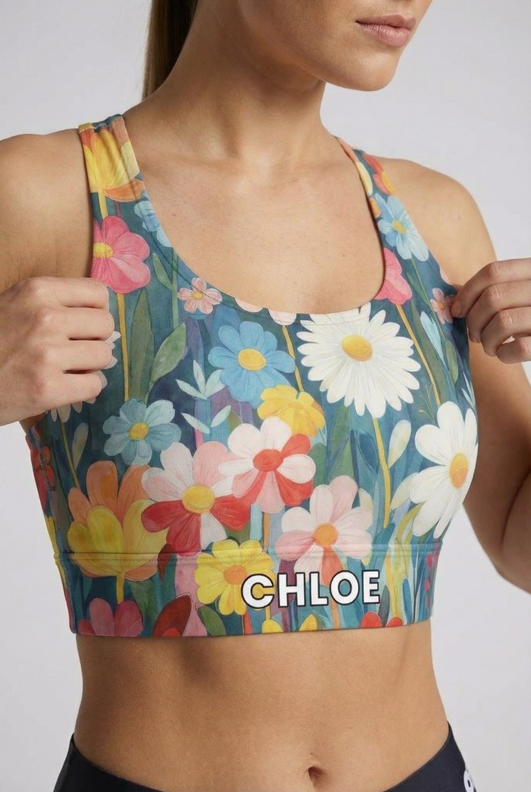 Watercolor floral sport bra with white daisies and custom name 'CHLOE' on waistband.