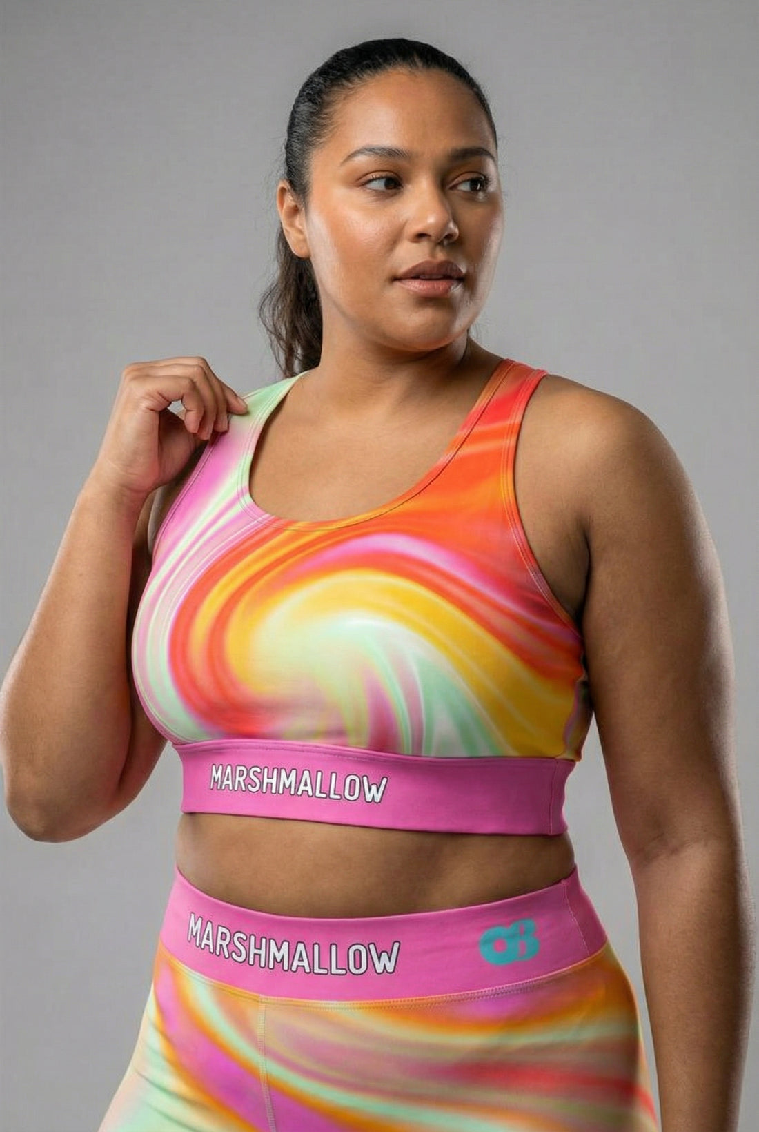 Front view of pastel tie-dye sports bra in peach, yellow, mint, and pink, featuring 'MARSHMALLOW' printed on the bubblegum pink waistband.