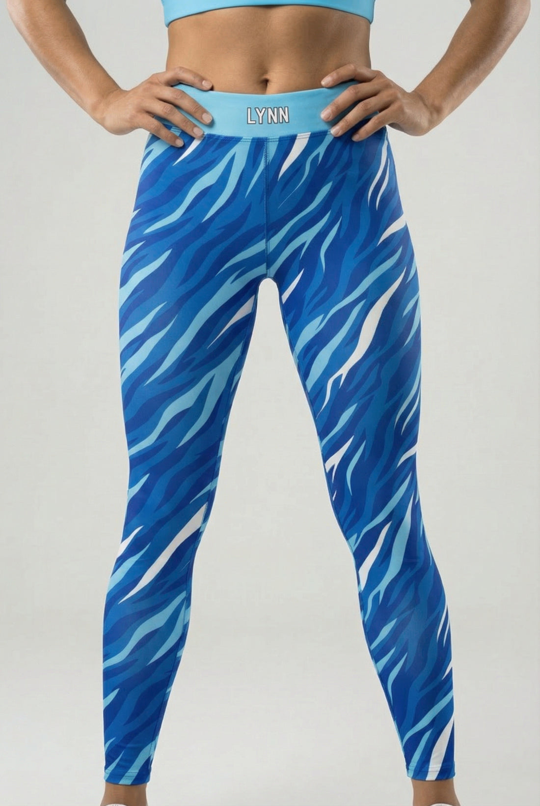 Front view of high-waisted leggings featuring royal blue, navy, and white tiger stripes, with 'LYNN' printed on the solid sky blue waistband.