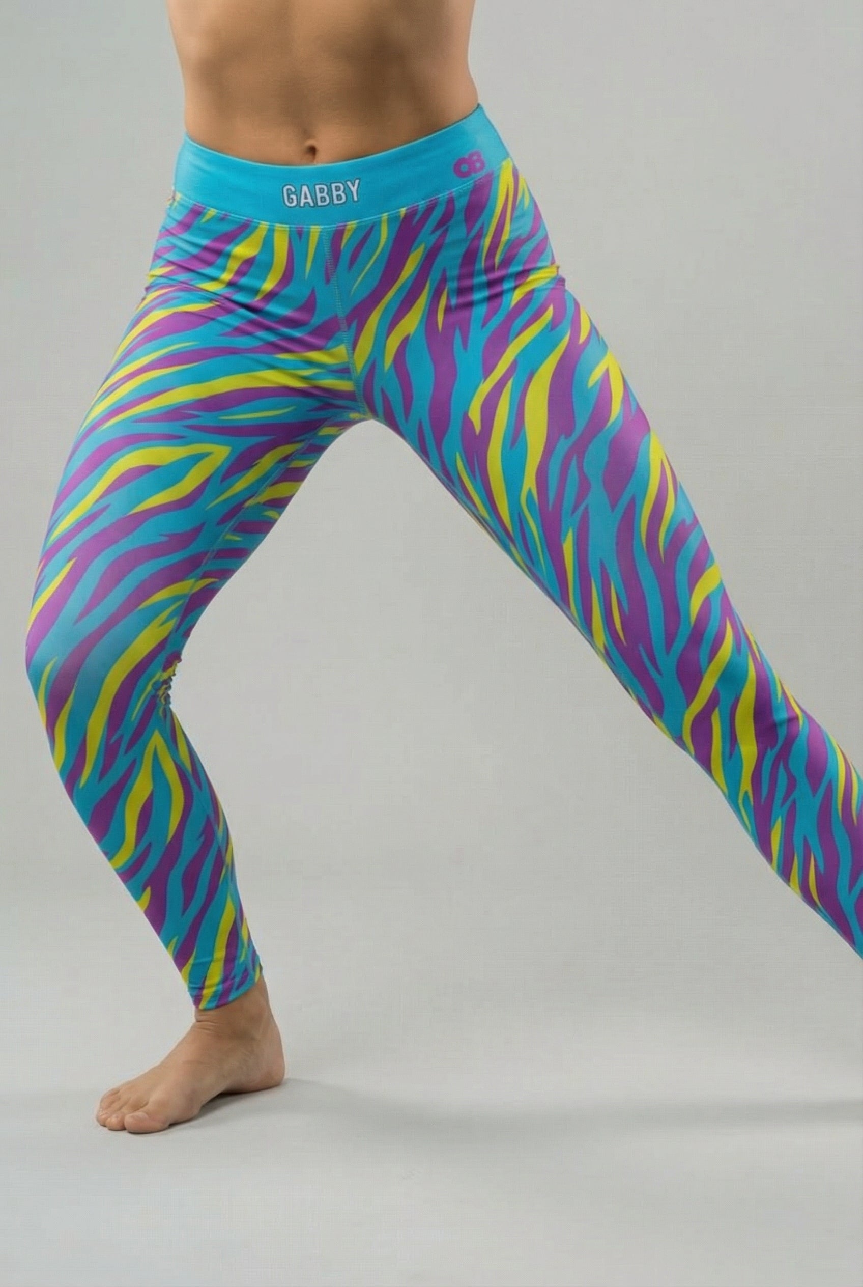 Front view of high-waisted leggings featuring bright cyan, electric yellow, and purple tiger stripes, with 'GABBY' printed on the solid cyan blue waistband