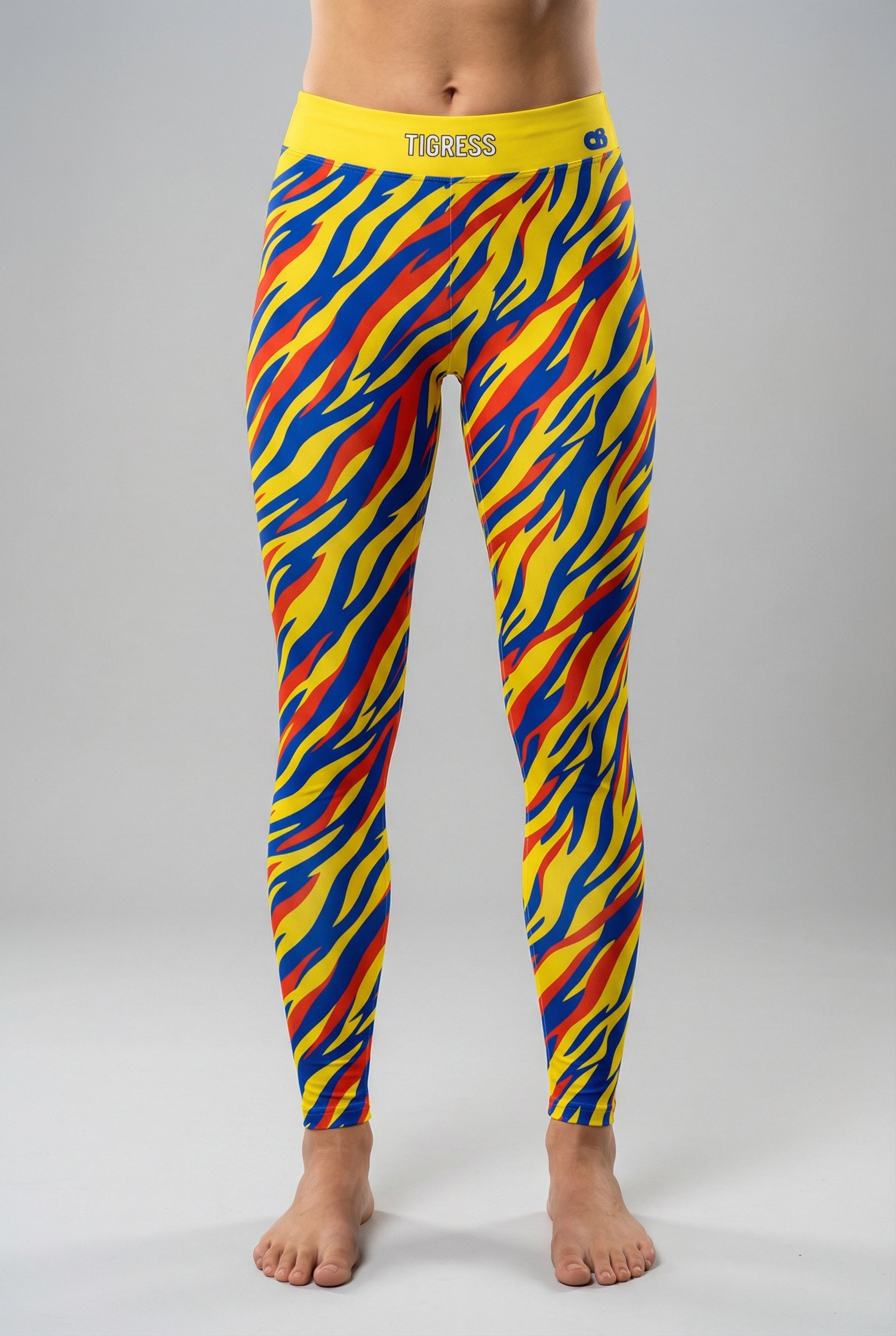 Front view of high-waisted leggings with pop-art tiger stripes in yellow, blue, and red, featuring 'TIGRESS' printed on the solid yellow waistband.