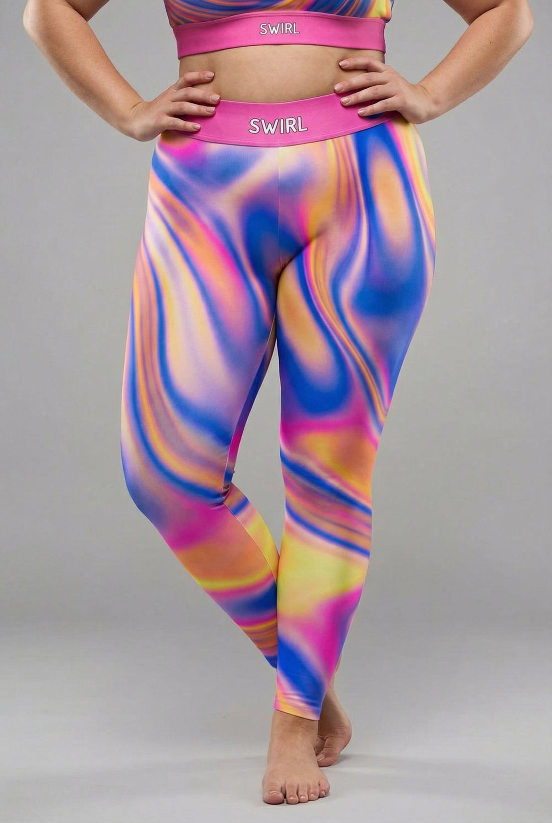 Front view of vibrant tie-dye swirl leggings in royal blue, magenta, yellow, and orange, featuring 'SWIRL' printed on the solid magenta waistband.
