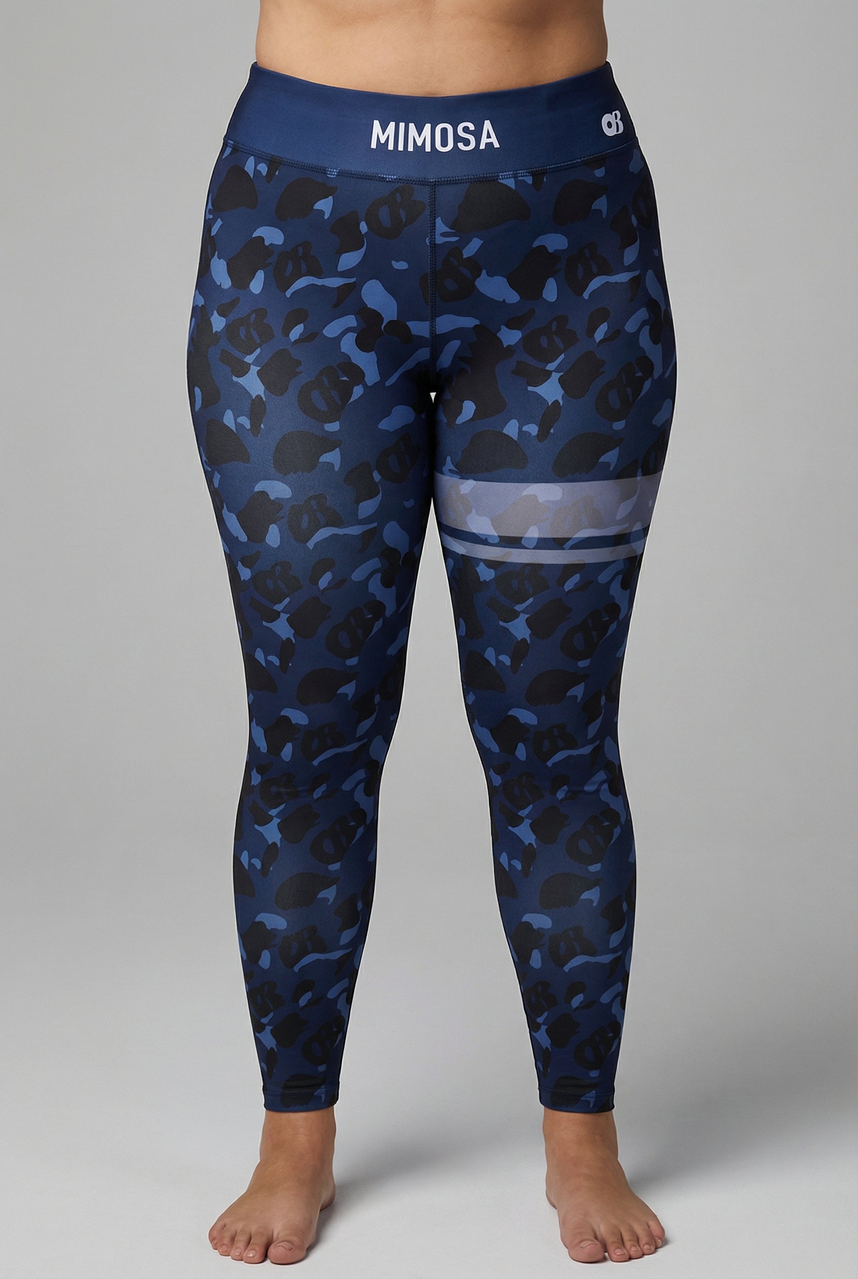 Front view of navy blue camouflage leggings with hidden 'OB' monogram shapes, featuring white stripes on the left thigh and 'MIMOSA' printed on the navy waistband.
