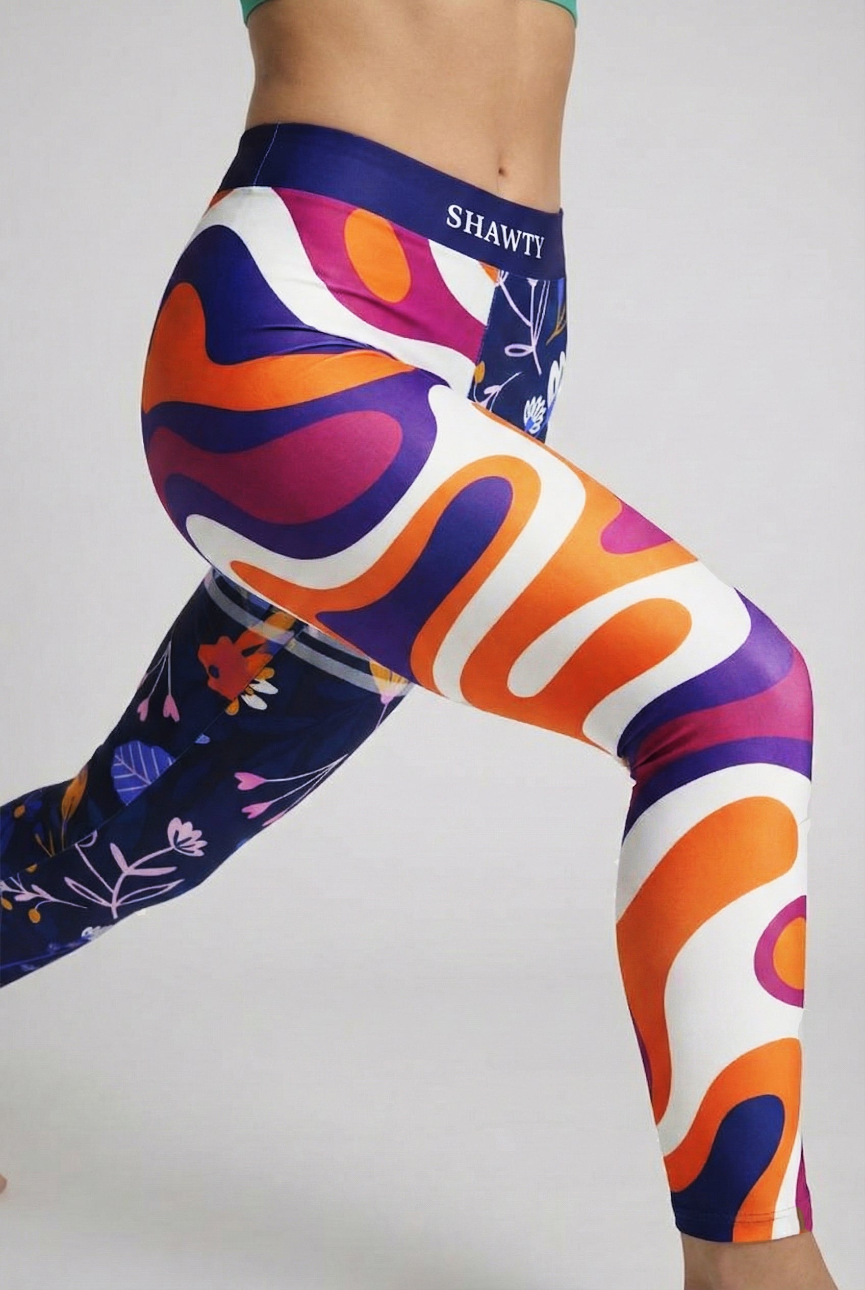 Split-leg leggings featuring orange/purple swirls on one side and navy floral print on the other, with custom text 'SHAWTY' on waistband.