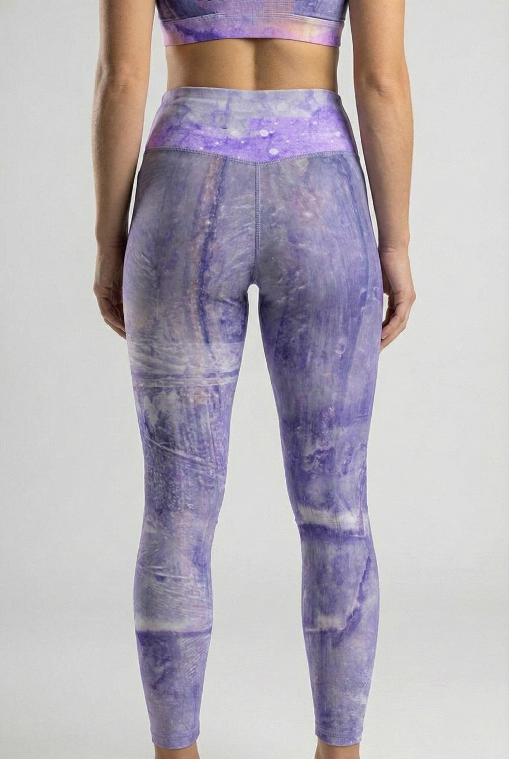 Person wearing purple tie-dye leggings on a plain background