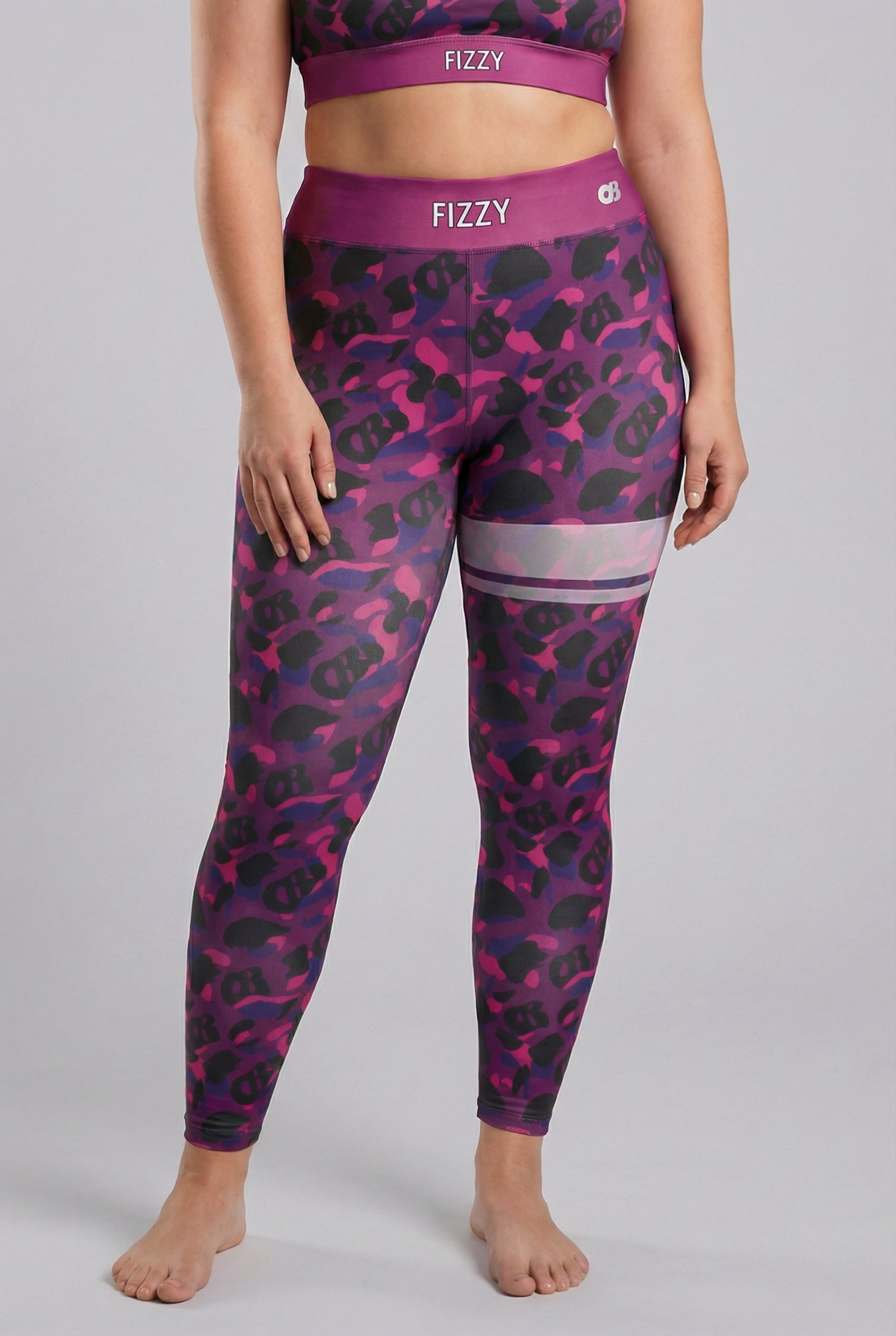 Front view of purple camouflage leggings with hidden 'OB' monogram shapes, featuring white stripes on the left thigh and 'FIZZY' printed on the plum waistband.