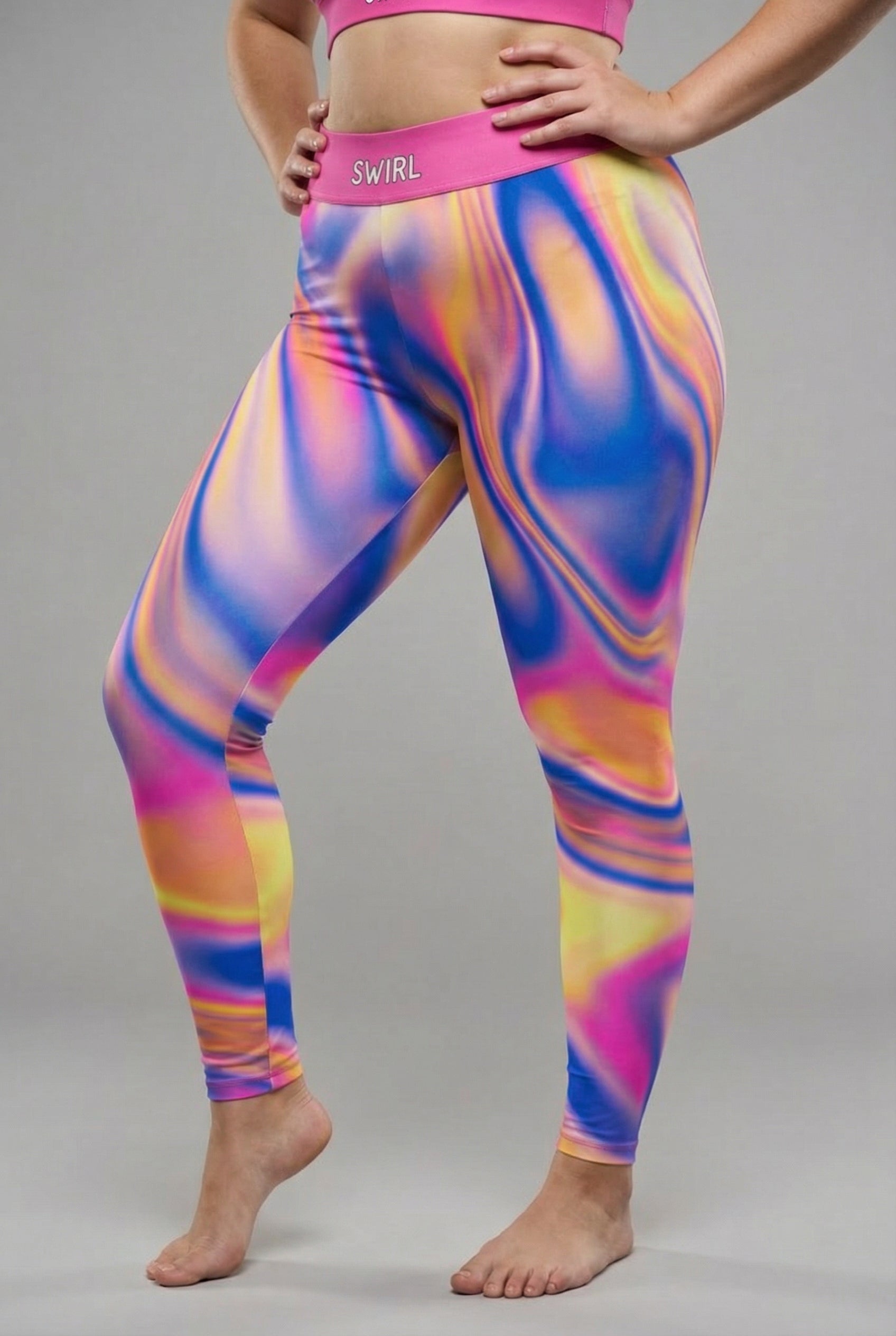 Front view of vibrant tie-dye swirl leggings in royal blue, magenta, yellow, and orange, featuring 'SWIRL' printed on the solid magenta waistband.