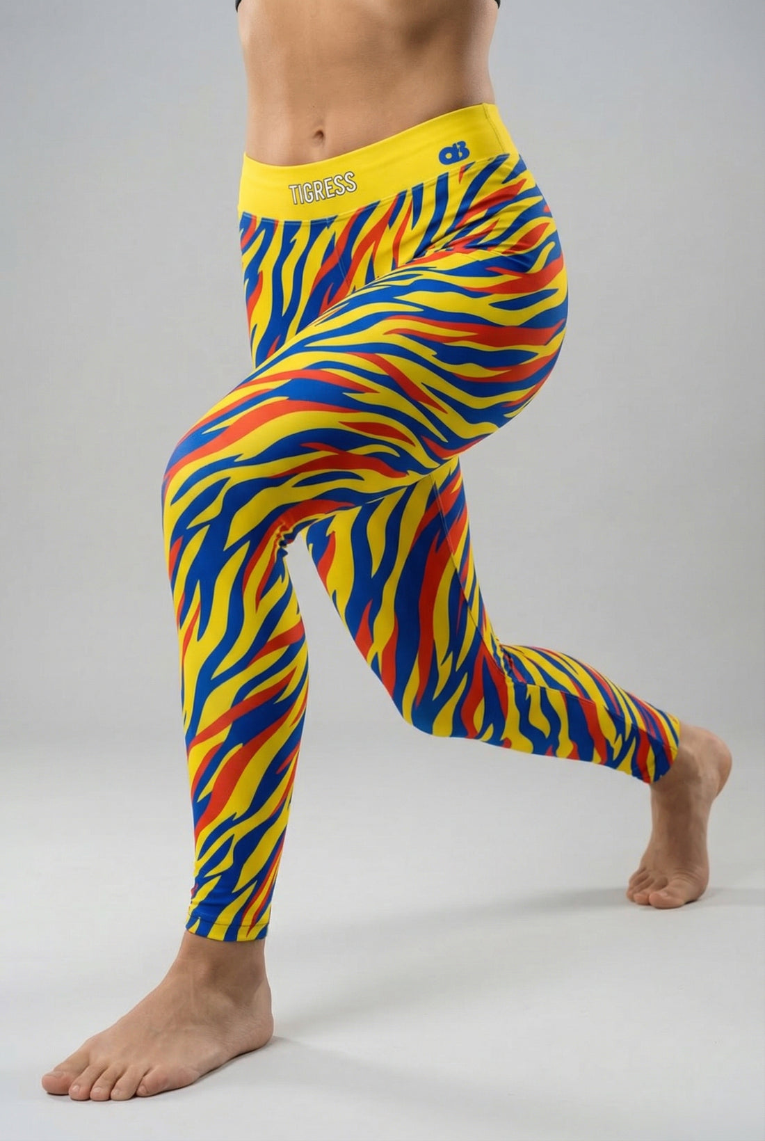 Front view of high-waisted leggings with pop-art tiger stripes in yellow, blue, and red, featuring 'TIGRESS' printed on the solid yellow waistband.