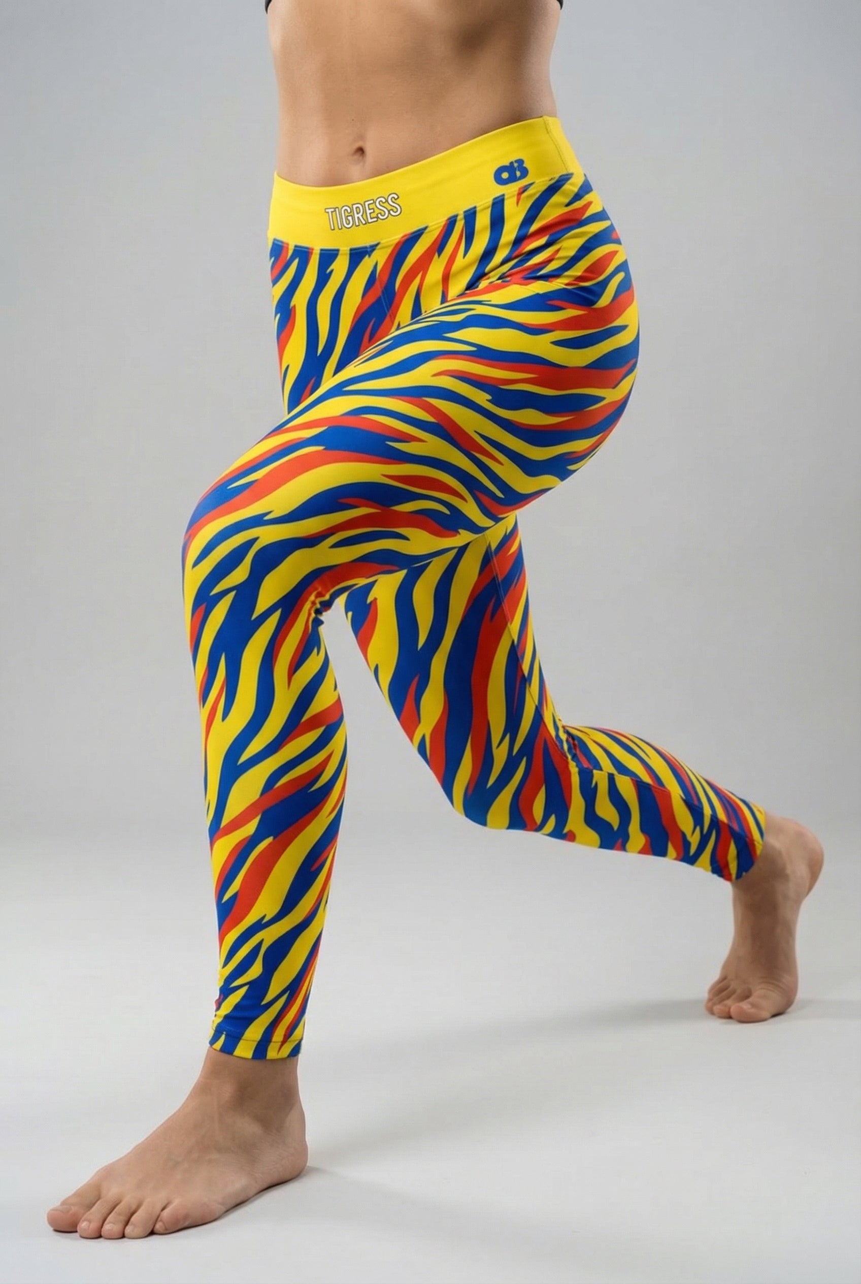 Front view of high-waisted leggings with pop-art tiger stripes in yellow, blue, and red, featuring 'TIGRESS' printed on the solid yellow waistband.