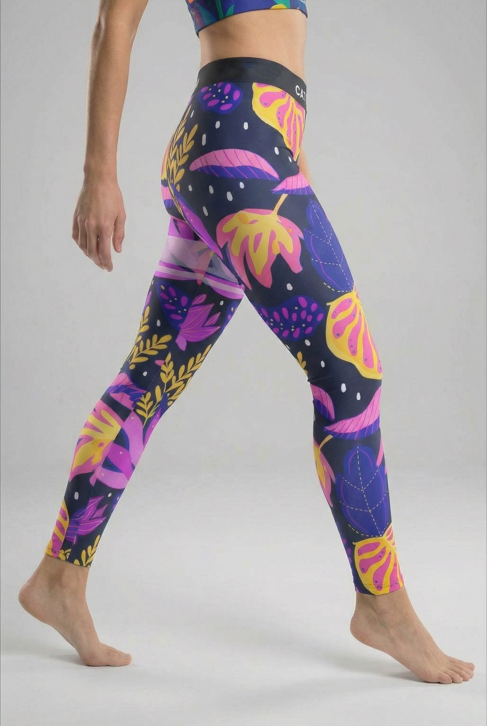 Colorful leaf-patterned leggings worn by a person on a plain background