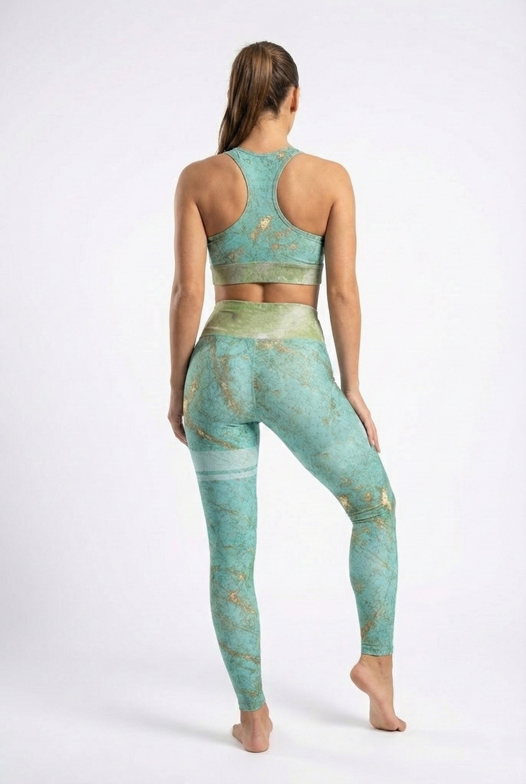 Woman wearing a green and gold athletic outfit on a white background